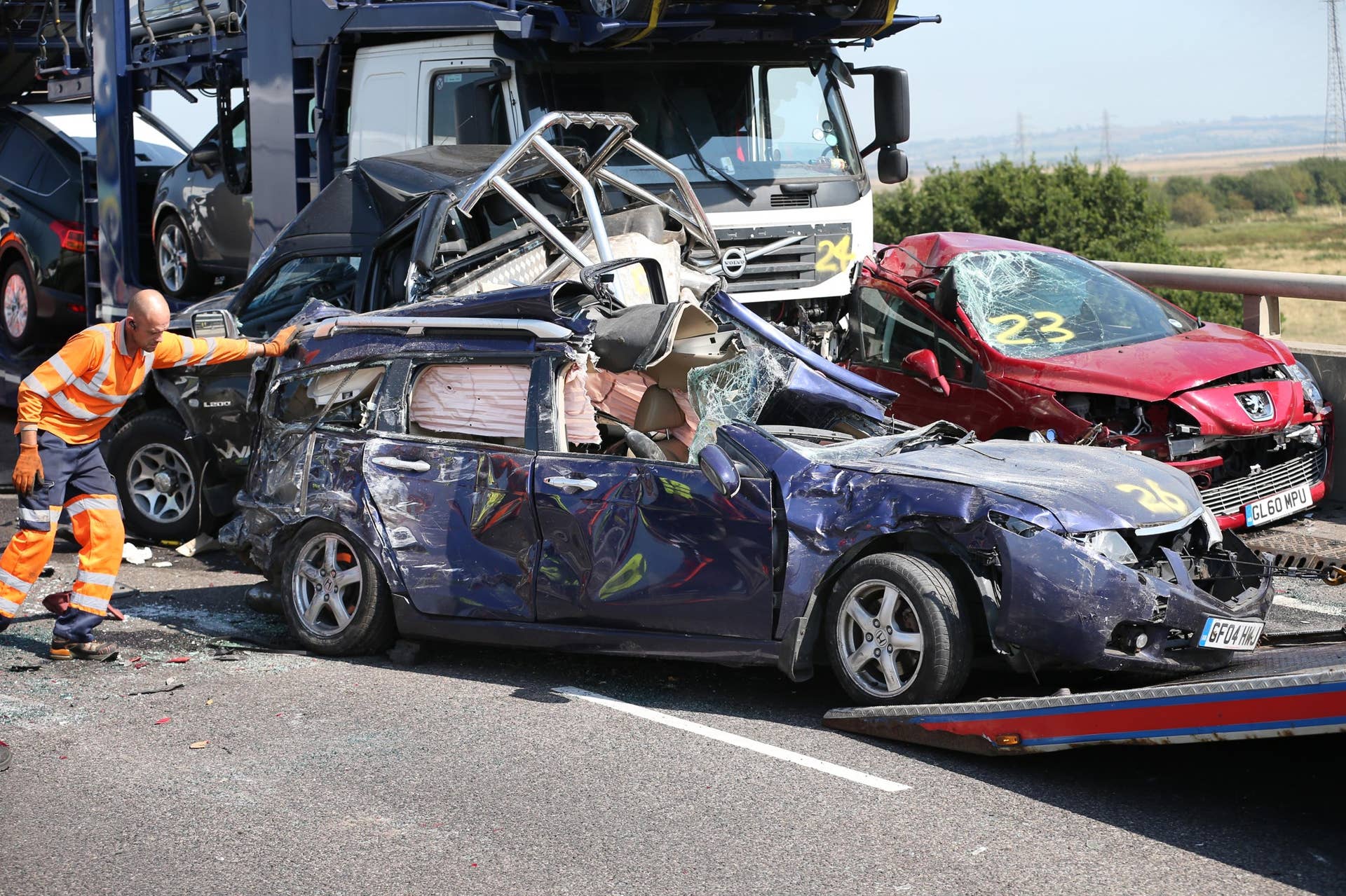 ISLE OF SHEPPEY, KENT - SEPTEMBER 05: A vehicle recovery worker pushes a car onto a trailer at major traffic accident on the A249 Sheppey crossing bridge in Kent on September 5, 2013 in Isle of Sheppey, Kent. Over 130 vehicles were involved in the series of accidents, with thick fog blamed for poor visibility. The crash occurred around 07:15AM BST, with at least 8 people suffering serious injuries, and approximately 60 people treated for minor injuries. (Photo by Peter Macdiarmid/Getty Images)