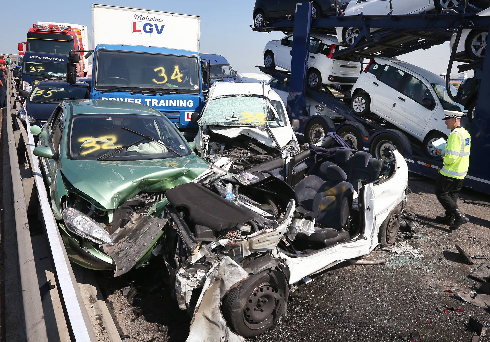 ISLE OF SHEPPEY, KENT - SEPTEMBER 05:  A policeman inspects the site of a major traffic accident on the A249 Sheppey crossing bridge in Kent on September 5, 2013 in Isle of Sheppey, Kent. Over 130 vehicles were involved in the series of accidents, with thick fog blamed for poor visibility. The crash occurred around 07:15AM BST, with at least 8 people suffering serious injuries, and approximately 60 people treated for minor injuries.  (Photo by Peter Macdiarmid/Getty Images)
