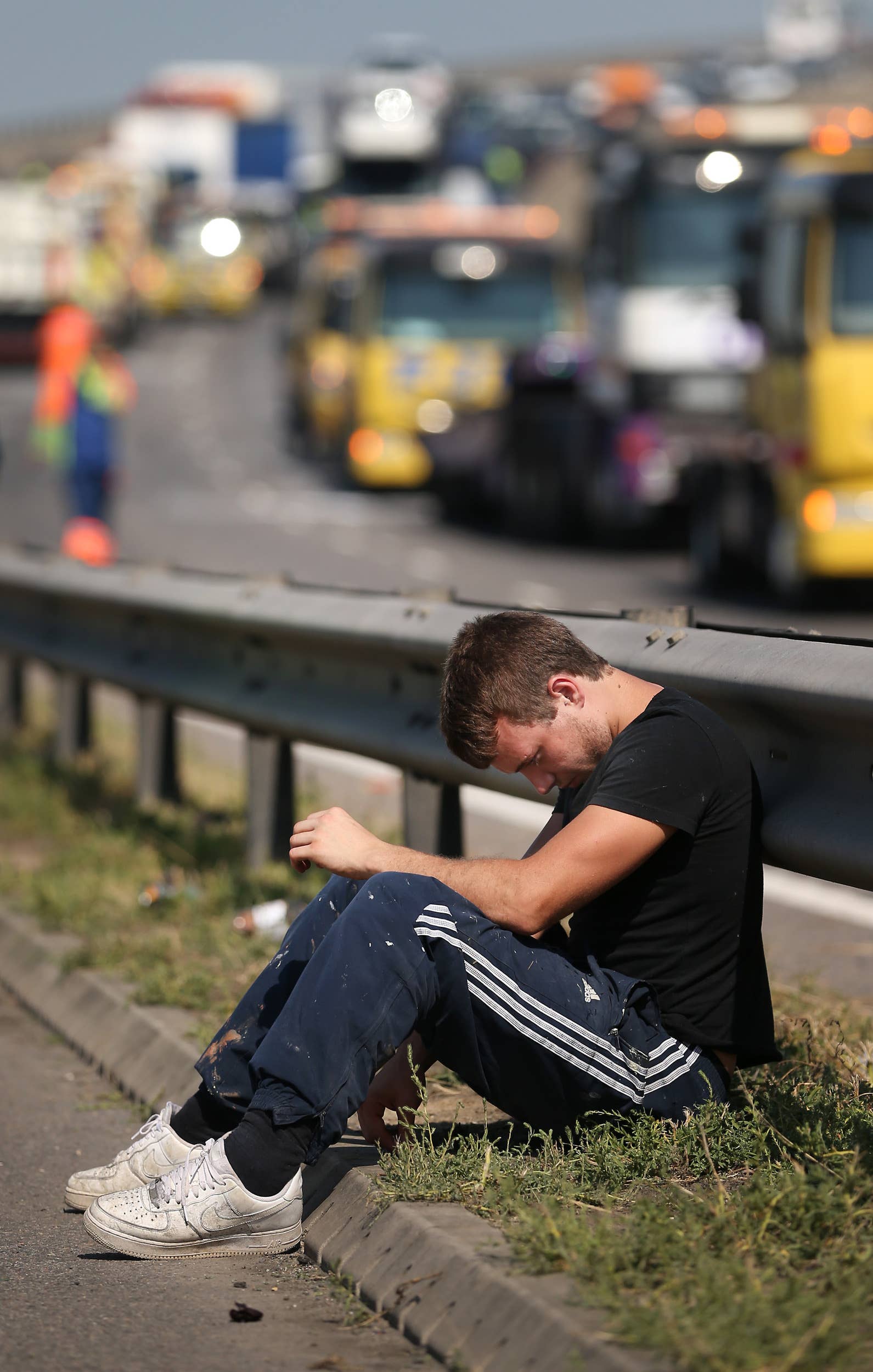 ISLE OF SHEPPEY, KENT - SEPTEMBER 05:  A man sits by the side of the road awaiting vehicle recovery after a major traffic accident on the A249 Sheppey crossing bridge in Kent on September 5, 2013 in Isle of Sheppey, Kent. Over 130 vehicles were involved in the series of accidents, with thick fog blamed for poor visibility. The crash occurred around 07:15AM BST, with at least 8 people suffering serious injuries, and approximately 60 people treated for minor injuries.  (Photo by Peter Macdiarmid/Getty Images)