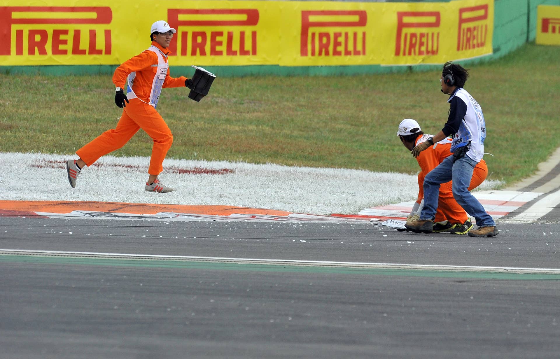 Marshals remove broken car pieces on the track during the Formula One Korean Grand Prix in Yeongam on October 6, 2013.  AFP PHOTO / JUNG YEON-JE        (Photo credit should read JUNG YEON-JE/AFP/Getty Images)