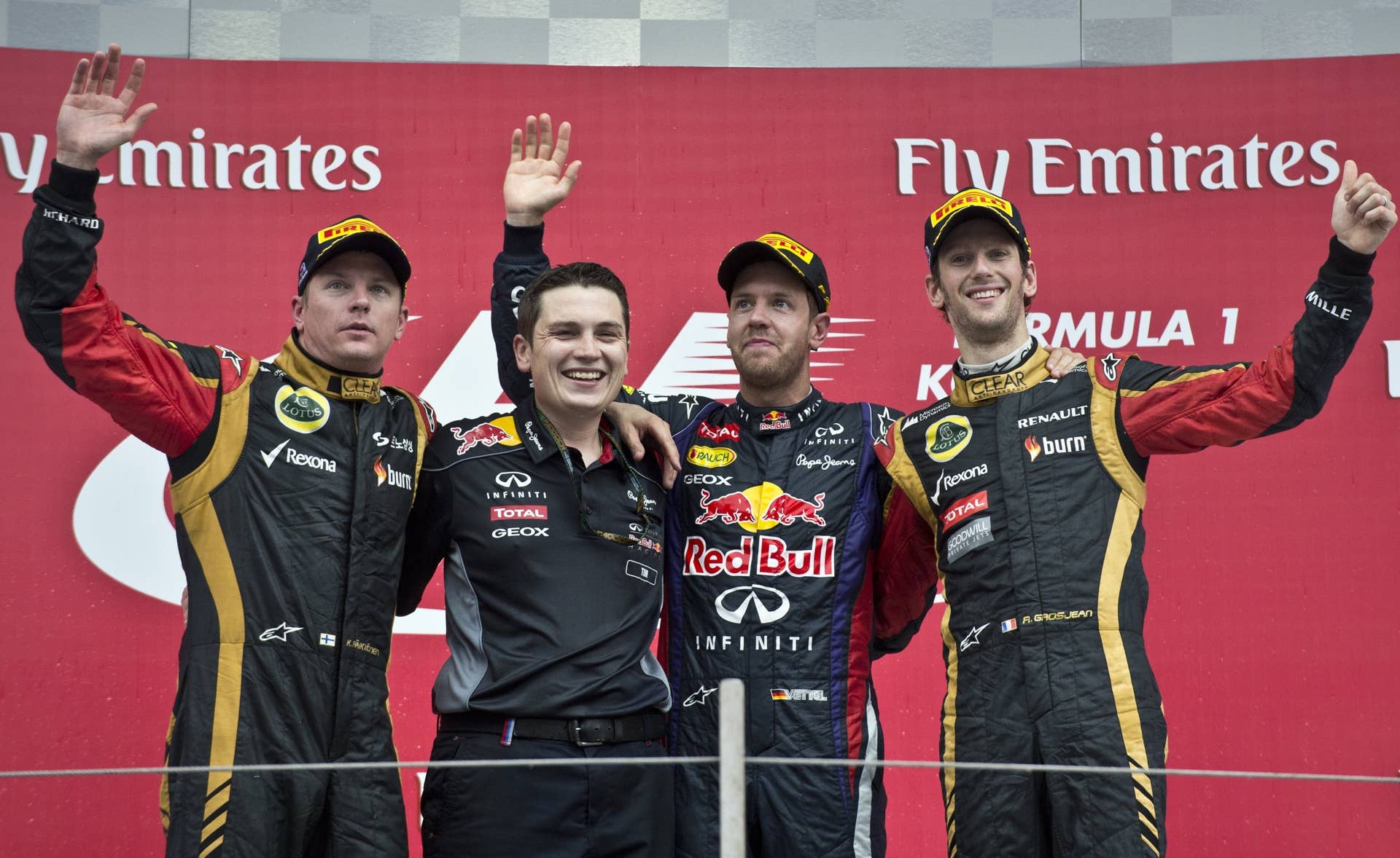 Red Bull driver Sebastian Vettel of Germany (2nd R) celebrates his victory on the podium with second-placed Lotus driver Kimi Raikkonen of Finland (L), third-placed Lotus driver Romain Grosjean of France (R) and Red Bull Performance Engineer Tim Malyon (2nd L) after the completion of the Formula One Korean Grand Prix in Yeongam on October 6, 2013.   AFP PHOTO/ Prakash SINGH        (Photo credit should read PRAKASH SINGH/AFP/Getty Images)