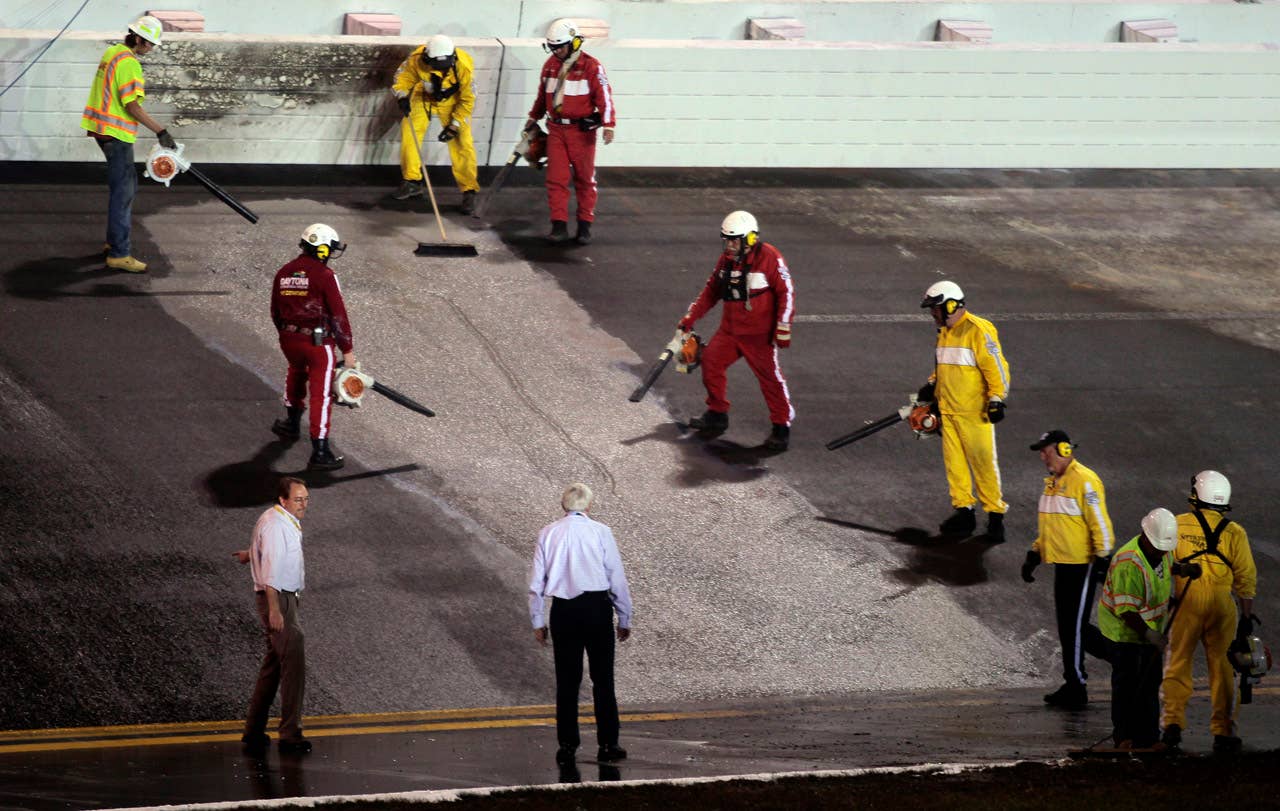 CORRECTS DAY AND DATE - Workers finish repairing an area in the track that was damaged by a fuel leak and fire during the NASCAR Daytona 500 auto race at Daytona International Speedway in Daytona Beach, Fla., late Monday, Feb. 27, 2012. (AP Photo/Bill Friel)