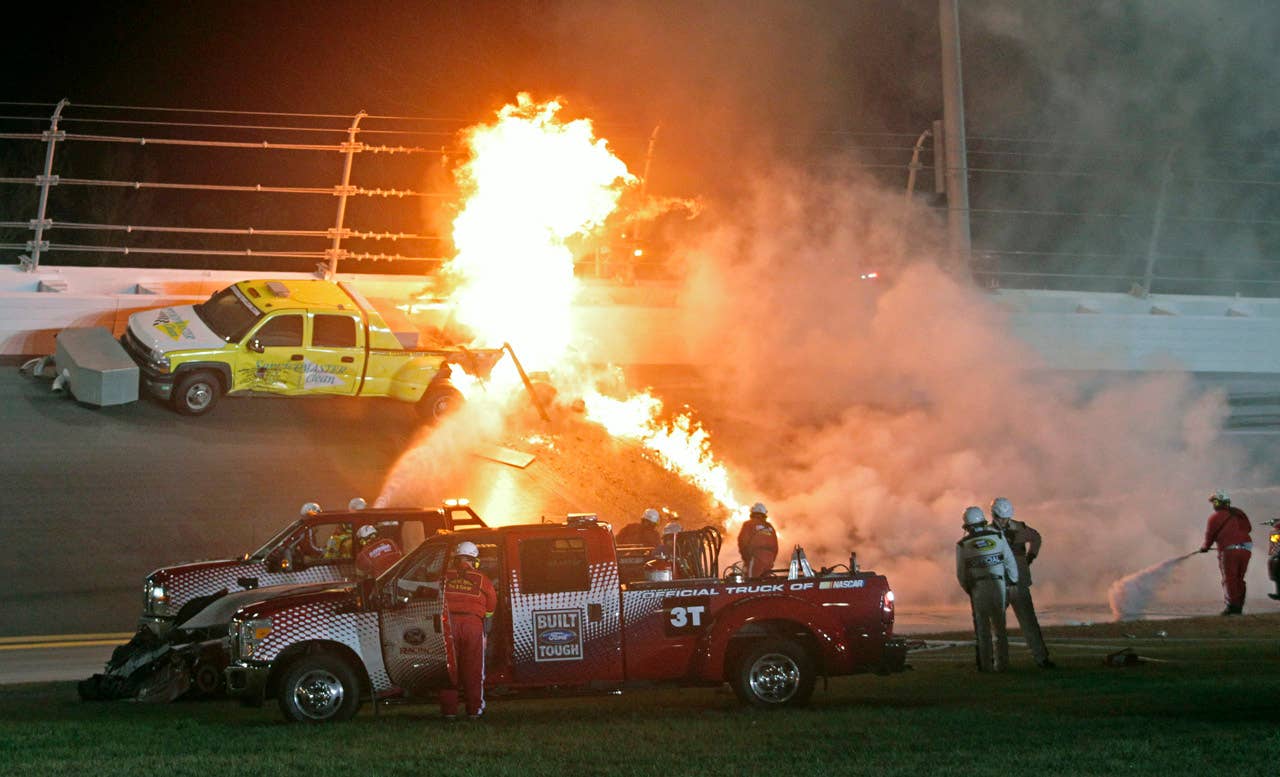 Emergency workers try to put out a fire after Juan Pablo Montoya's car struck the truck during the NASCAR Daytona 500 auto race at Daytona International Speedway in Daytona Beach, Fla., Monday, Feb. 27, 2012. (AP Photo/Bill Friel)