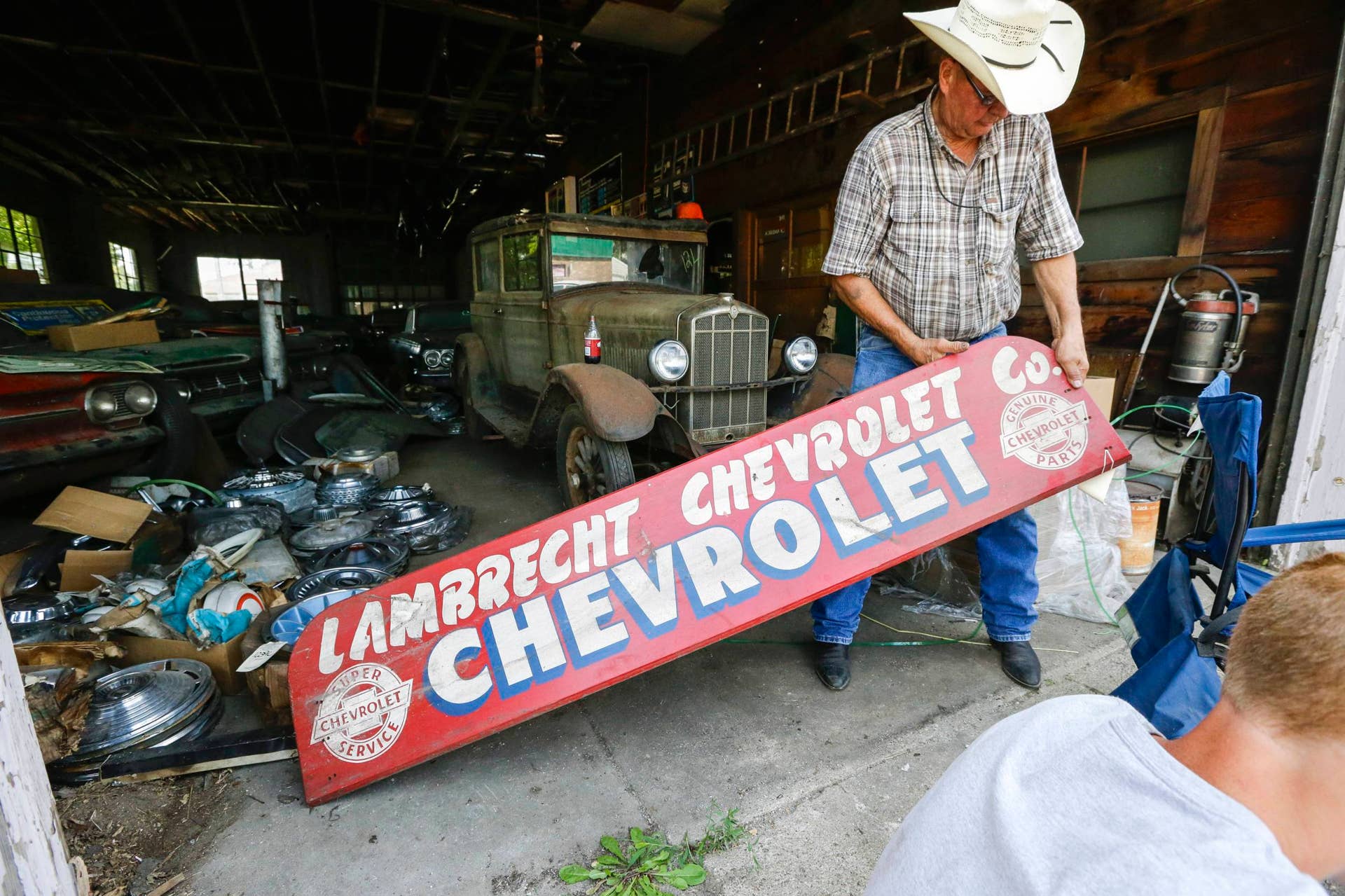 In this Aug. 12, 2013 photo, Art Nordstrom holds a sign at the former Lambrecht Chevrolet car dealership in Pierce, Neb. In September, bidders from at least a dozen countries and all 50 U.S. states will converge on Pierce, a town of about 1,800 in northeast Nebraska, for a two-day auction that will feature about 500 old cars and trucks, mostly Chevrolets that went unsold during the dealership?s five decades in business. About 50 have fewer than 20 miles on the odometer, and some are so rare that no one has established a price. The most valuable could fetch six-figure bids. (AP Photo/Nati Harnik)