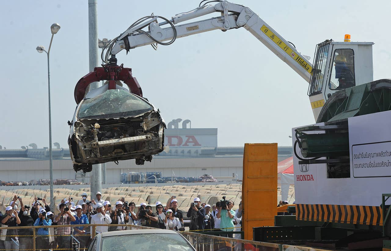 A Honda worker lifts a flood damaged car at the Honda factory in Ayutthaya province on December 27, 2011. Japanese car assembler Honda automobile (Thailand) started to scrap 1,055 cars which were damaged by the recent floods in Thailand, ensuring that damaged parts would not be sold, the company said in statement. AFP PHOTO/PORNCHAI KITTIWONGSAKUL (Photo credit should read PORNCHAI KITTIWONGSAKUL/AFP/Getty Images)