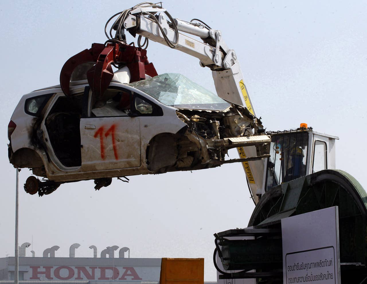 A Honda Jazz car hangs on a hydraulic claw before being destroyed during a destruction demonstration of the cars that were damaged because of the flood at Honda automobile plant in Ayutthaya province, central Thailand Tuesday, Dec. 27, 2011. The 1,055 unit of Honda cars, mostly Brio eco-cars and City subcompacts, were destroyed in an action to assure to customers that the flood-damaged cars will not be repaired and sold. (AP Photo/Apichart Weerawong)