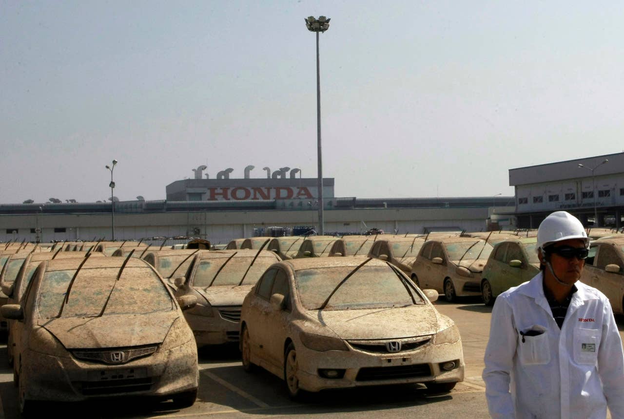 A worker walks in front of lines of Honda cars that were damaged by the flood before the destruction demonstration at Honda automobile plant in Ayutthaya province, central Thailand Tuesday, Dec. 27, 2011. The 1,055 unit of Honda cars, mostly Brio eco-cars and City subcompacts, were destroyed in an action to assure to customers that the flood-damaged cars will not be repaired and sold. (AP Photo/Apichart Weerawong)