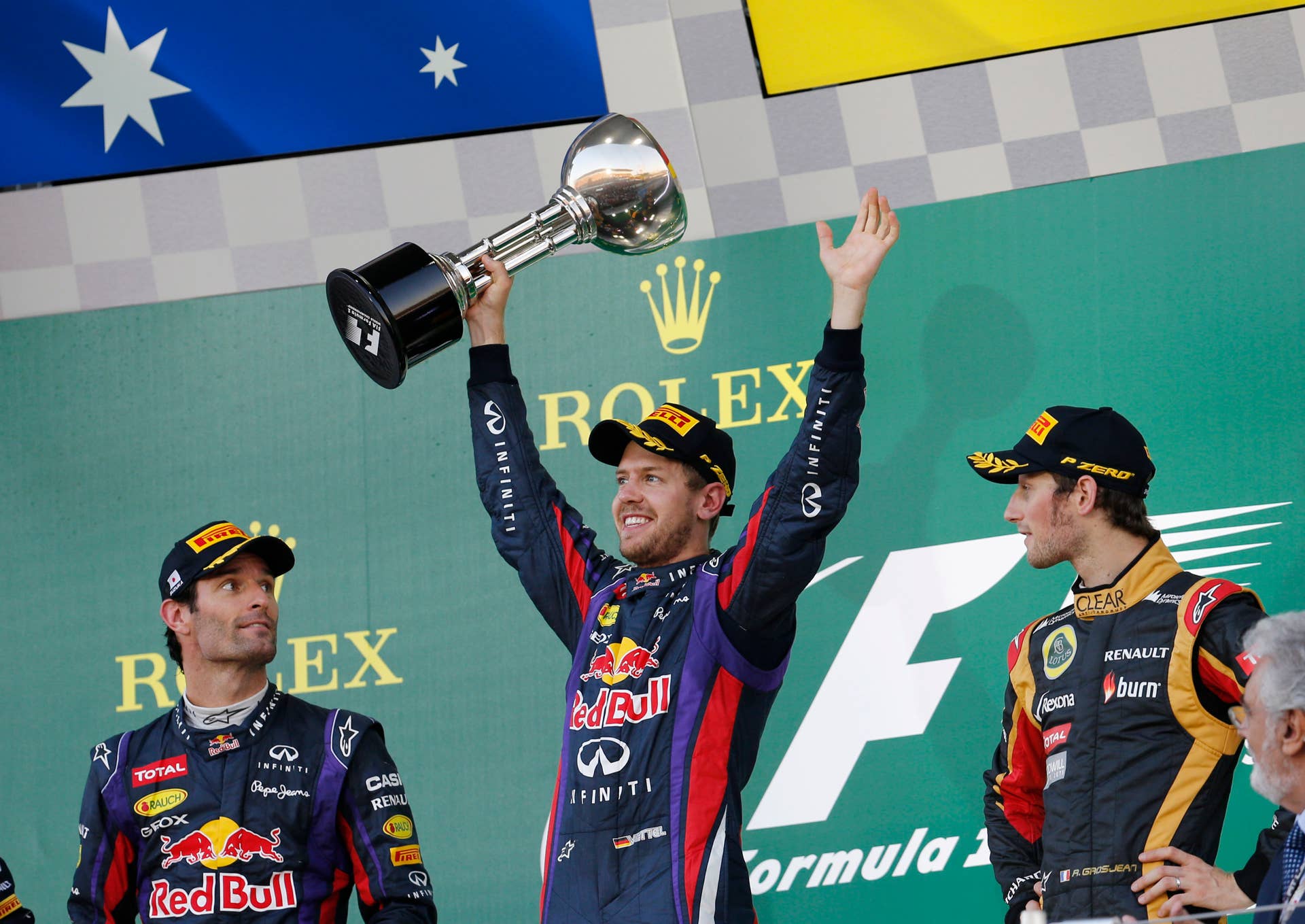 Red Bull driver Sebastian Vettel of Germany celebrates with the trophy after winning the Japanese Formula One Grand Prix at the Suzuka circuit in Suzuka, Japan, Sunday, Oct. 13, 2013. At left is second placed Red Bull driver Mark Webber of Australia, and at right third placed Lotus driver Romain Grosjean of France. (AP Photo/Shizuo Kambayashi)