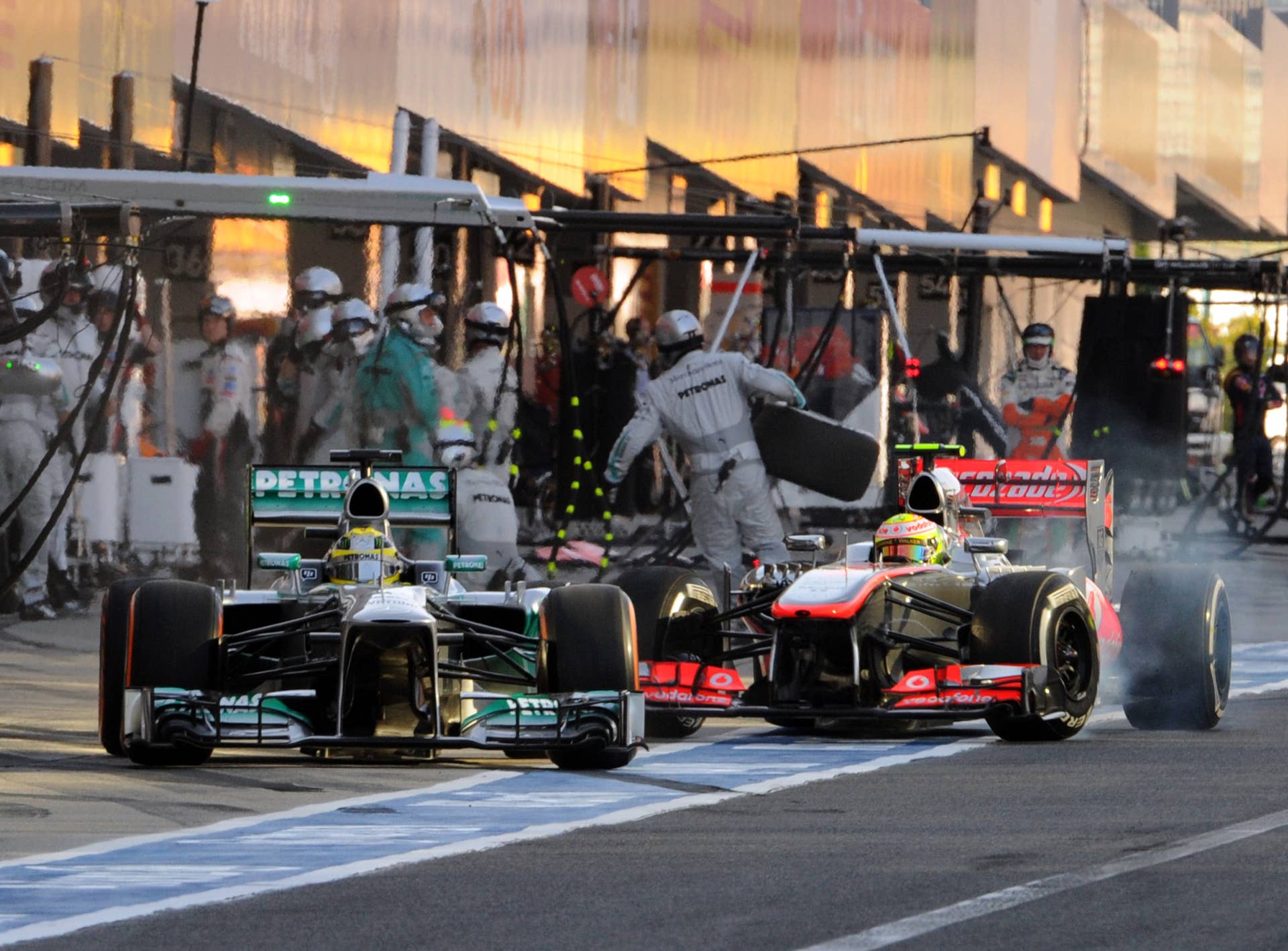 Mercedes driver Nico Rosberg of Germany (L) receives a penalty while pitting out in front of McLaren driver Sergio Perez Mendoza of Mexico (R) coming into his pit during the Formula One Japanese Grand Prix in Suzuka on October 13, 2013.    AFP PHOTO / POOL / TOSHIFUMI KITAMURA        (Photo credit should read TOSHIFUMI KITAMURA/AFP/Getty Images)