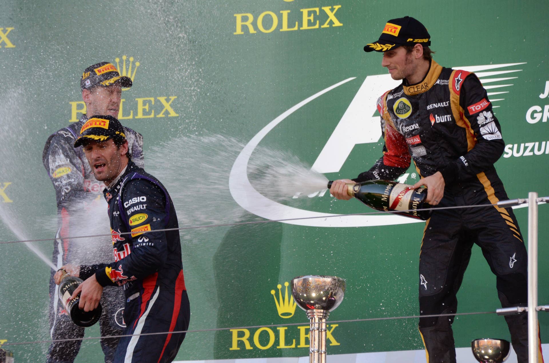 First-placed Red Bull driver Sebastian Vettel (L) of Germany, second-placed his teammate Mark Webber (2nd L) of Australia and third-placed Lotus driver Romain Grosjean (R) of France spray champagne during the awarding ceremony of the Formula One Japanese Grand Prix in Suzuka on October 13, 2013.    AFP PHOTO/Toru YAMANAKA        (Photo credit should read TORU YAMANAKA/AFP/Getty Images)