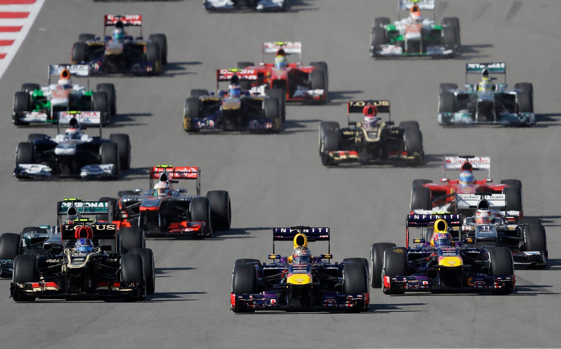 Lotus driver Romain Grosjean of Switzerland, left, pulls into second place next to Red Bull driver Mark Webber of Australia as Red Bull driver Sebastian Vettel of Germany leads the start of the Formula One U.S. Grand Prix auto race at the Circuit of the Americas, Sunday, Nov. 17, 2013, in Austin, Texas. (AP Photo/Eric Gay)