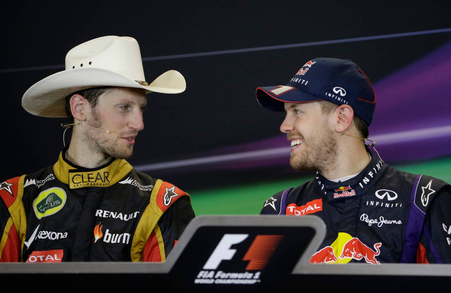 Lotus driver Romain Grosjean, left, of Switzerland wears a cowboy hat during a press conference with Red Bull driver Sebastian Vettel of Germany following the Formula One U.S. Grand Prix auto race at the Circuit of the Americas, Sunday, Nov. 17, 2013, in Austin, Texas. Vettel was first and Grosjean finished second. (AP Photo/Darron Cummings)