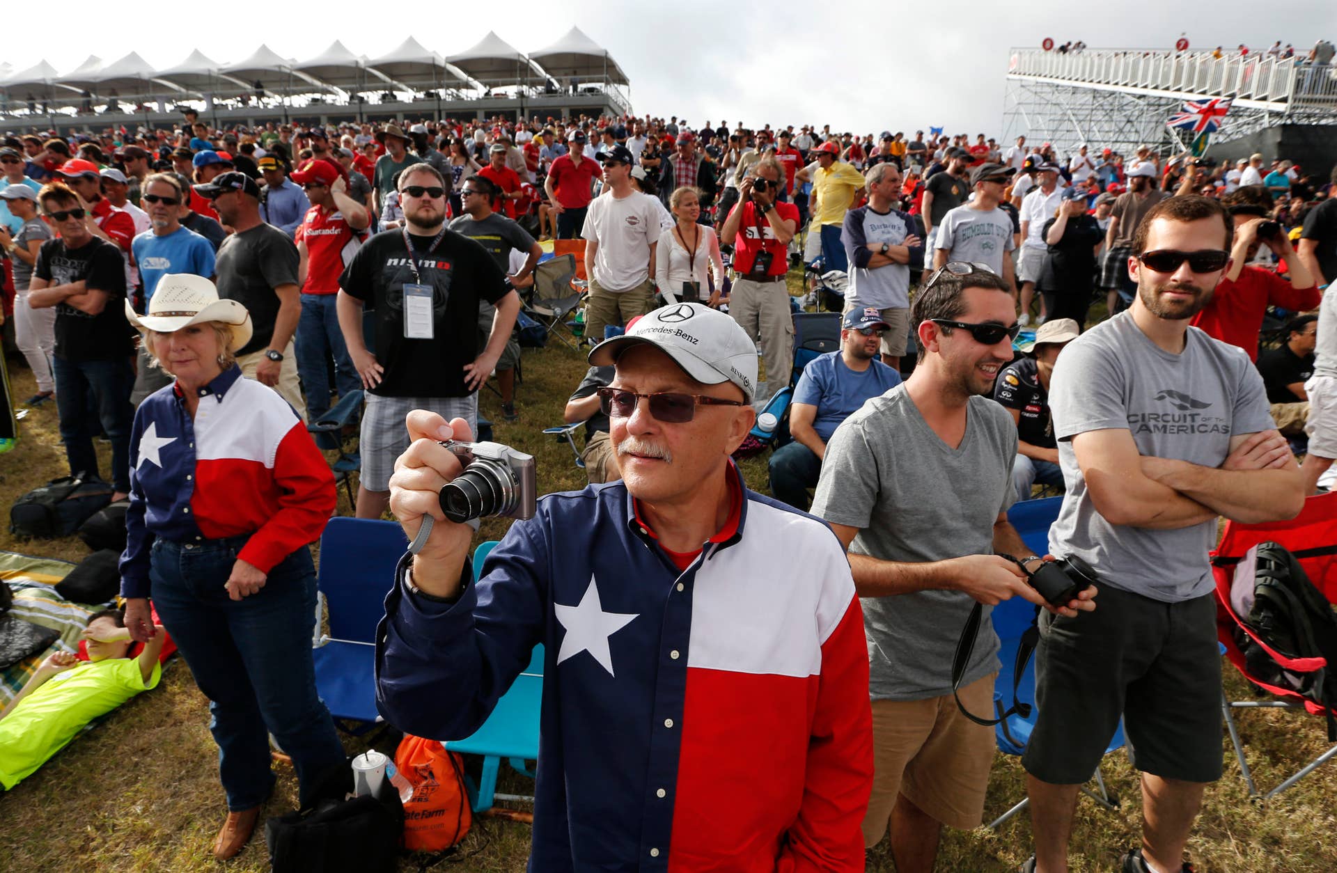 Tim Jones, center, from El Paso, Texas, takes photographs of an early race before the Formula One U.S. Grand Prix auto race at the Circuit of the Americas, Sunday, Nov. 17, 2013, in Austin, Texas. (AP Photo/David J. Phillip)
