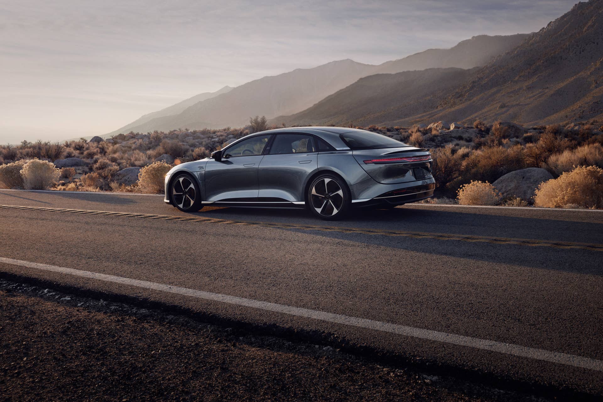 A Lucid Air Pure driving on a desert road