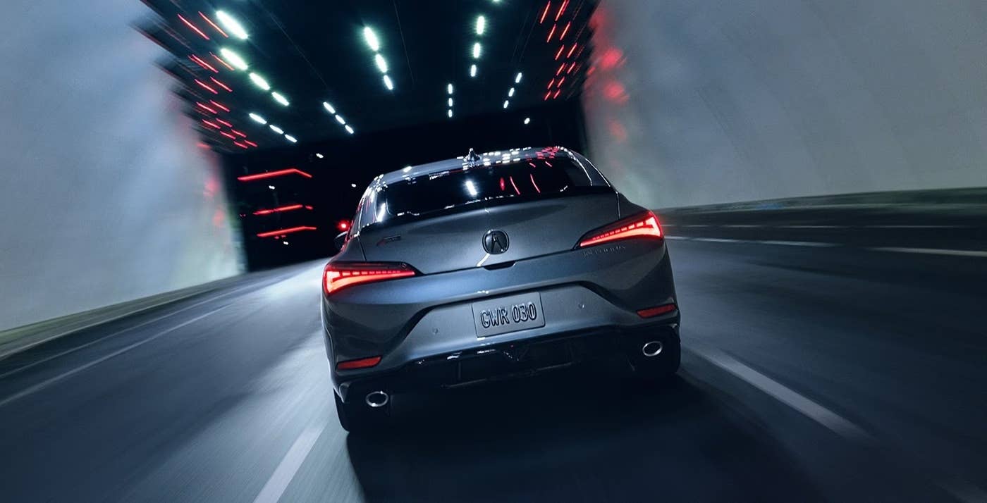 Rear view of a silver2025 Acura Integra driving at night