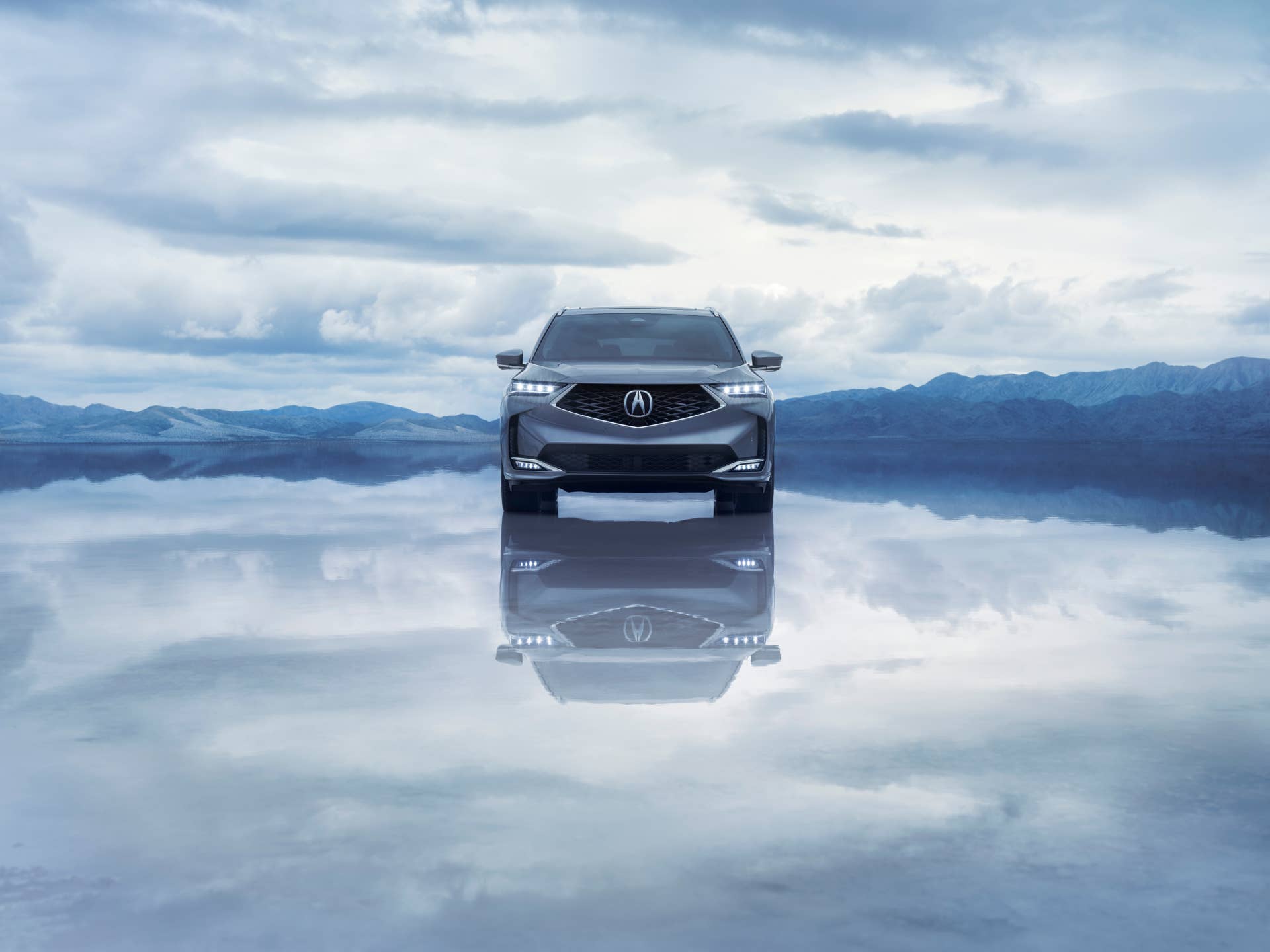Front view of a 2025 Acura MDX with Advance Package seemingly floating on a mountain lake