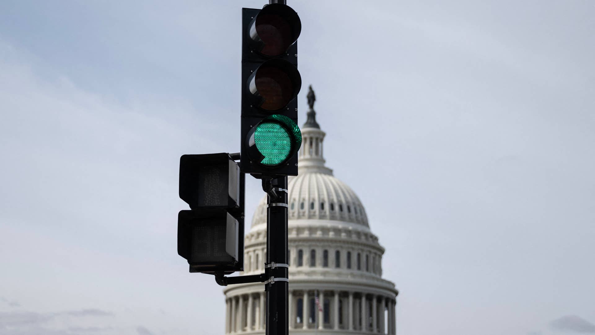 A green traffic light near the US Capitol in the background in Washington, DC, on March 8, 2024. US senators were racing against the clock March 8 to vote on a package of funding bills for key federal agencies to avert a partial government shutdown ahead of a midnight deadline. The $460 billion package, already passed by the House of Representatives, is expected to get broad support, but lawmakers were yet to lock in a timeline for holding a vote, amid Republican infighting over spending cuts. (Photo by ANDREW CABALLERO-REYNOLDS / AFP) (Photo by ANDREW CABALLERO-REYNOLDS/AFP via Getty Images)