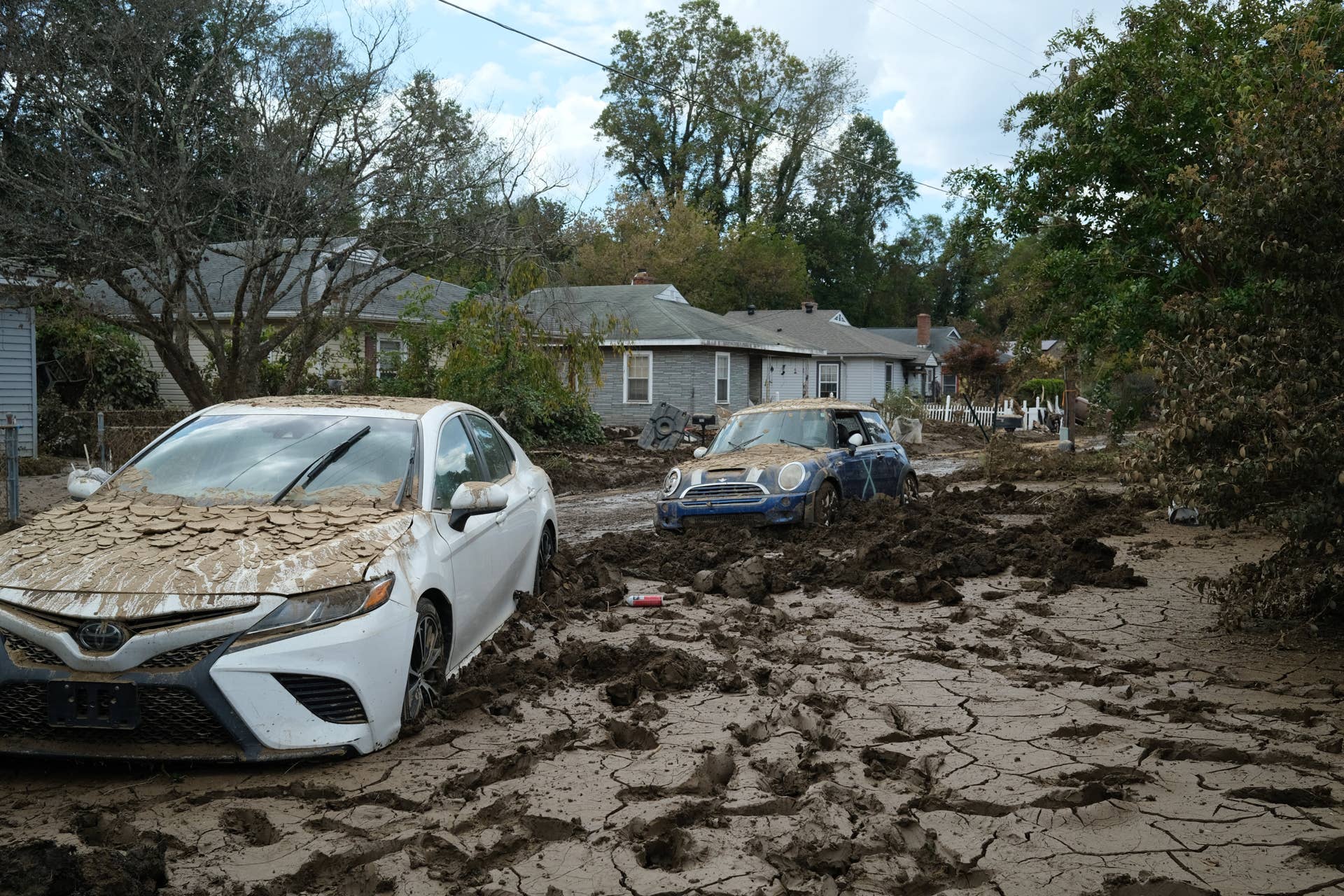 Cars are caked in mud on a street washed away by flooding from Hurricane Helene in Swannanoa, North Carolina, on October 3, 2024. More than 200 people are now confirmed dead after Hurricane Helene carved a path of destruction through several US states, officials said, making it the second deadliest storm to hit the US mainland in more than half a century. (Photo by Ulysse BELLIER / AFP) (Photo by ULYSSE BELLIER/AFP via Getty Images)