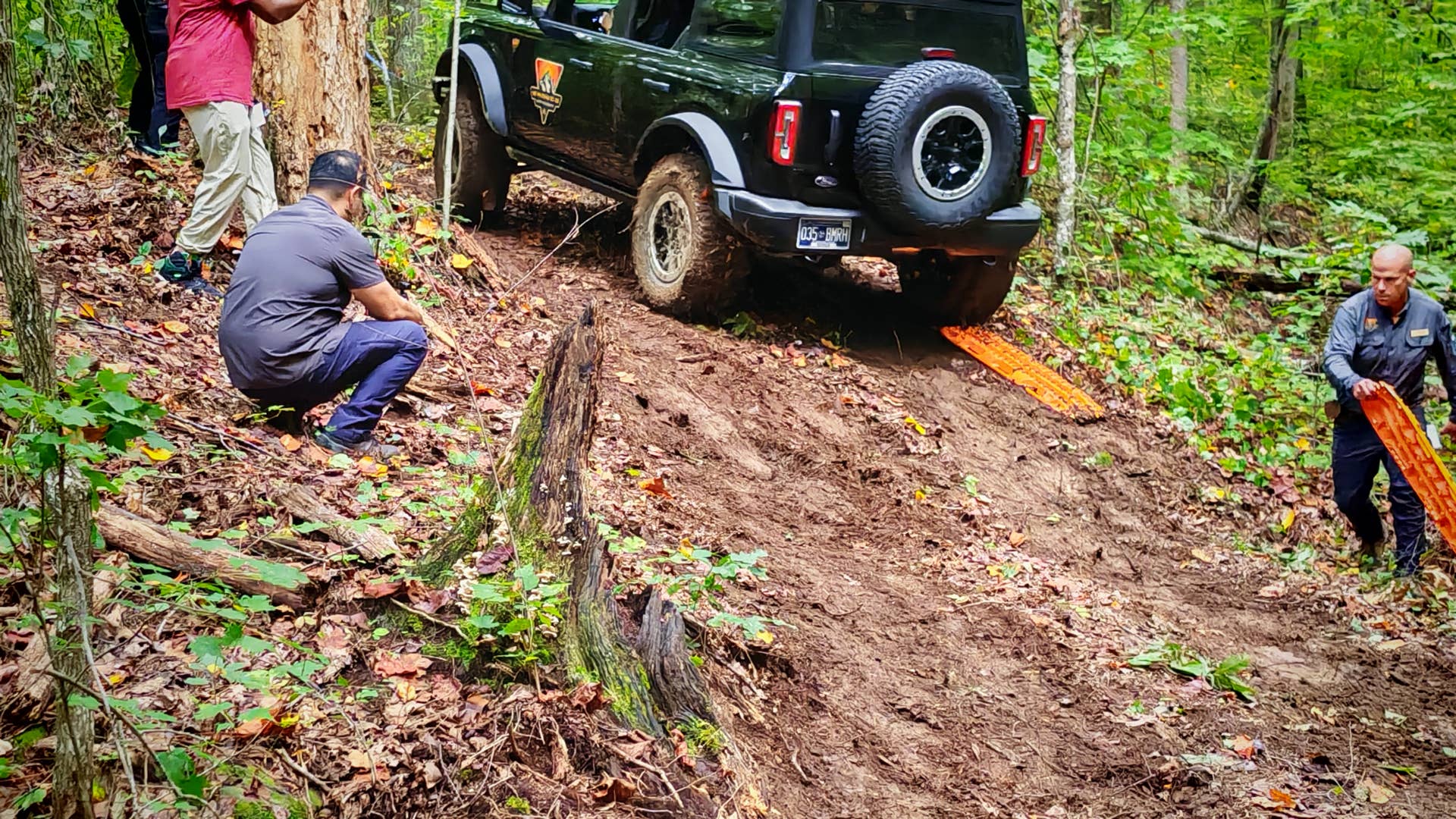 Traction boards being used to help a Ford Bronco up a muddy slope