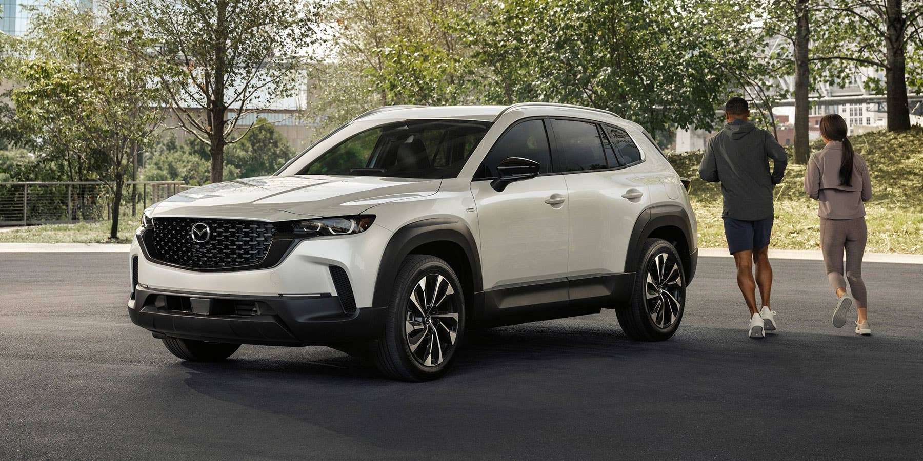 A couple jogging around a parked Mazda CX-50 Hybrid