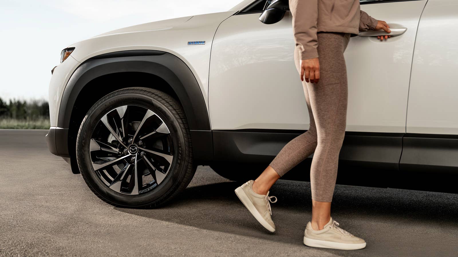 A closeup image of the front of a Mazda CX-50 Hybrid as a woman opens its door