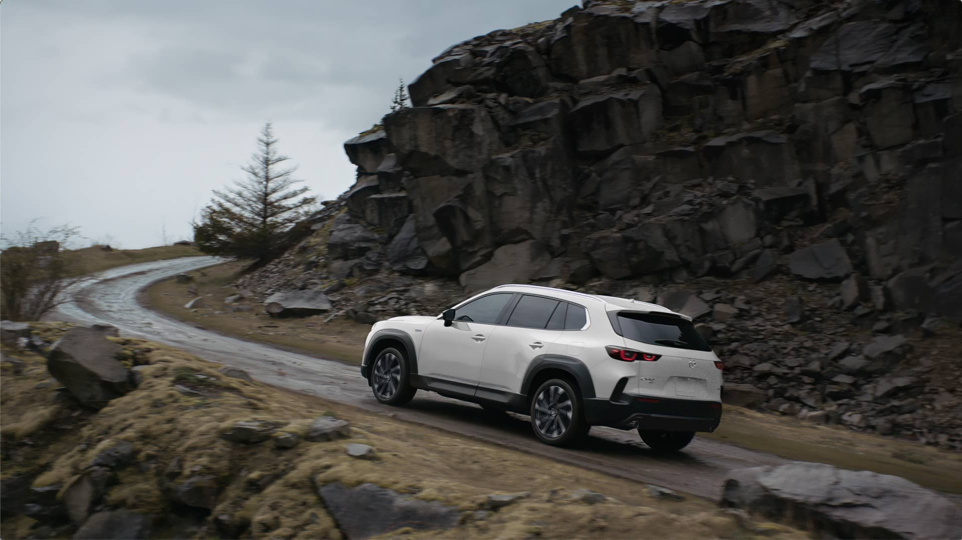 The Mazda CX-50 Hybrid driving up a rocky slope