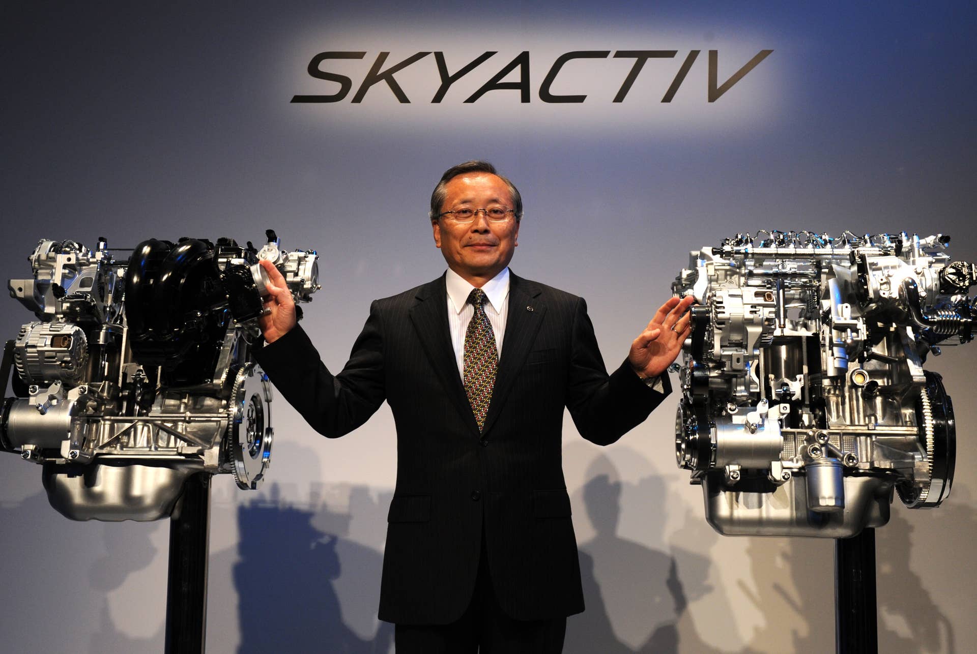 Mazda motors President Takashi Yamanouchi stands among the company's next-generation gasoline and diesel engines, SKYACTIVE-G