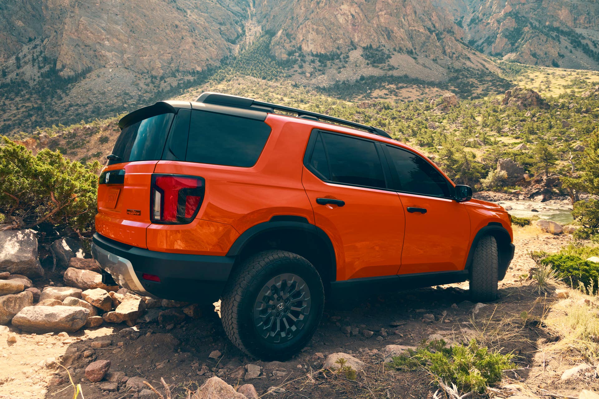 2026 Honda Passport TrailSport in Sunset Orange rear angled view off-road driving