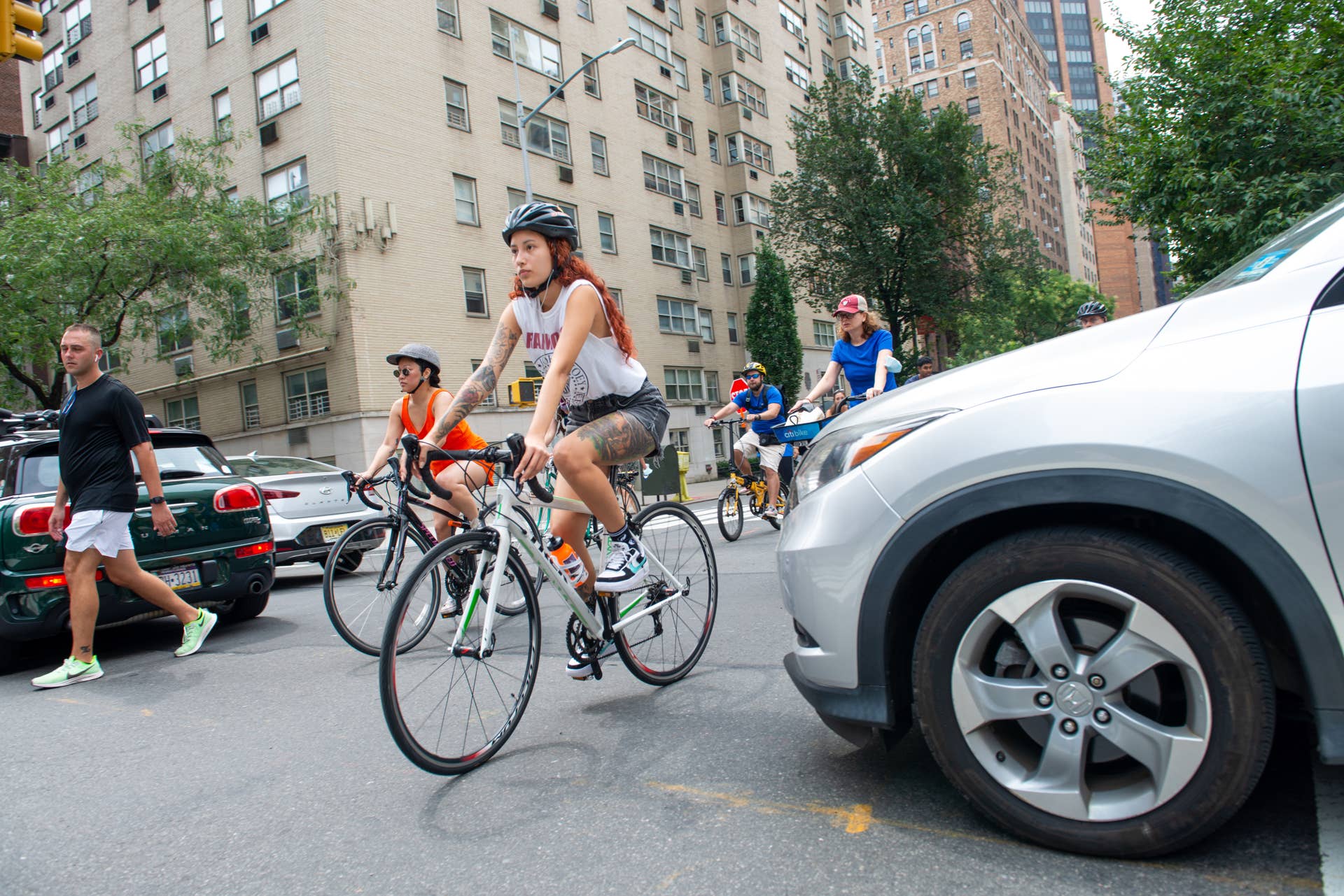 NEW YORK, NEW YORK - AUGUST 07: People riding bicycles move past cars blocking an intersection along Park Avenue during Summer Streets by the New York City Department of Transportation on August 07, 2021 in New York City. Summer Streets is an annual initiative that opens up seven miles of Park Avenue from the Brooklyn Bridge to Central Park allowing people to play, run, walk, and bike. (Photo by Alexi Rosenfeld/Getty Images)