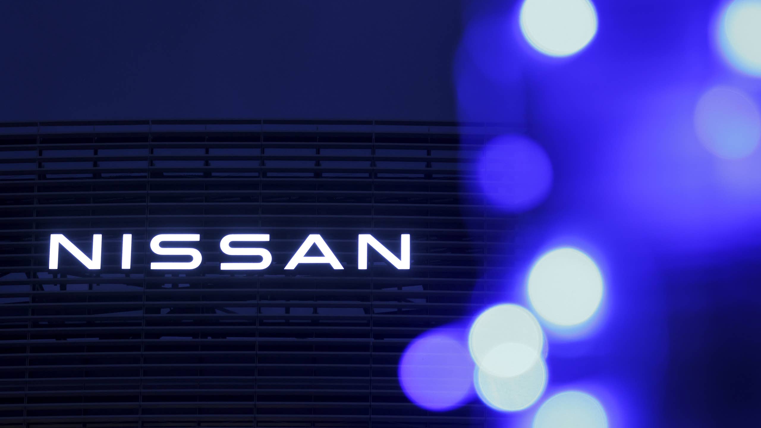 Illuminated signage atop the Nissan Motor Co. global headquarters at dusk in Yokohama, Japan, on Tuesday, Nov. 12, 2024. A fund controlled by Effissimo Capital Management Pte, which has a history of pushing for change in Japan, has taken a stake in Nissan just days after cratering profit and sales induced by an outdated lineup, pricey dealer incentives and lack of hybrids in North America forced the Japanese carmaker to slash jobs and production. Photographer: Kiyoshi Ota/Bloomberg via Getty Images