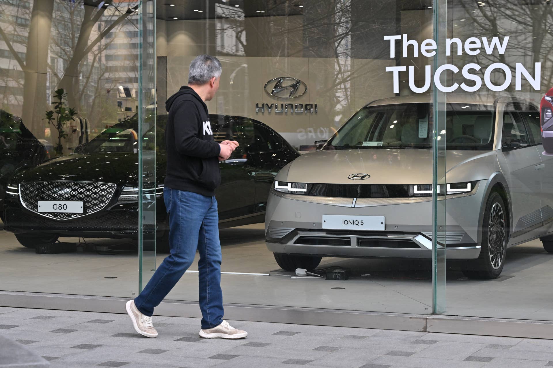 A man walks past in front of a car dealership of Hyundai Motor in Seoul on March 27, 2024.