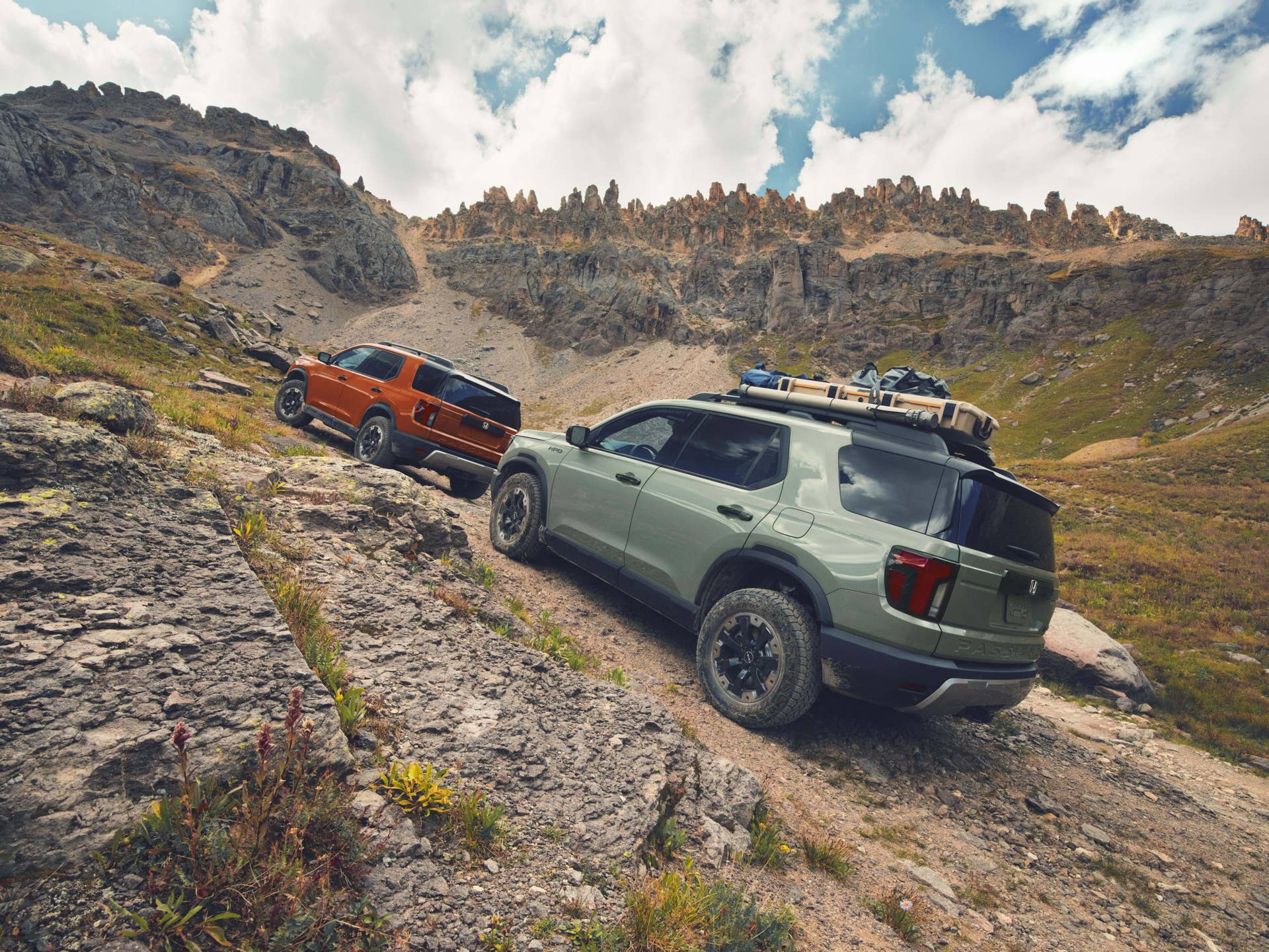 2026 Honda Passport TrailSport in Sunset Orange and Ash Green rear angled view off-road driving