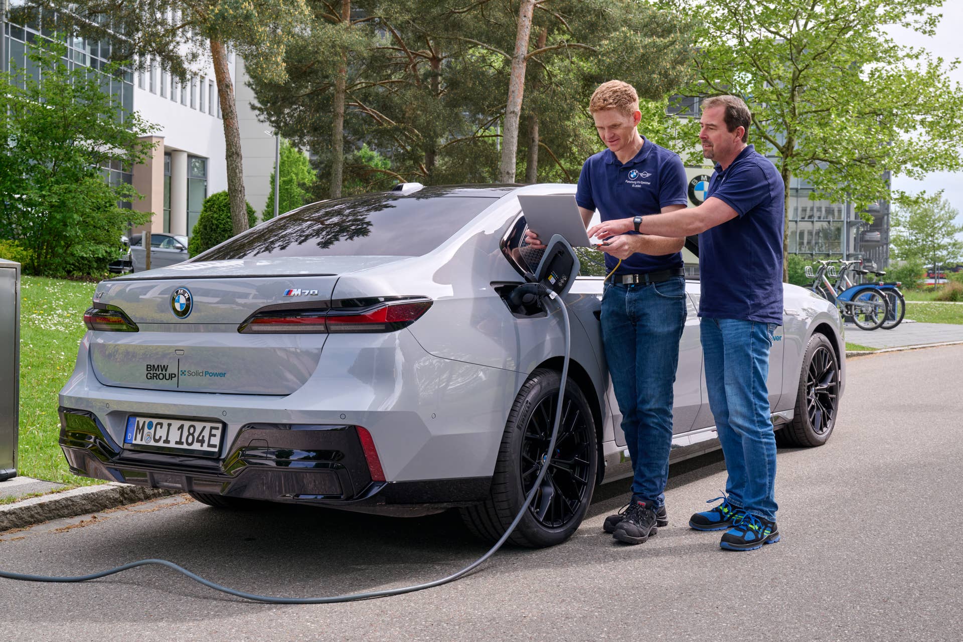 two bmw engineers on a computer next to the BMW i7 M70