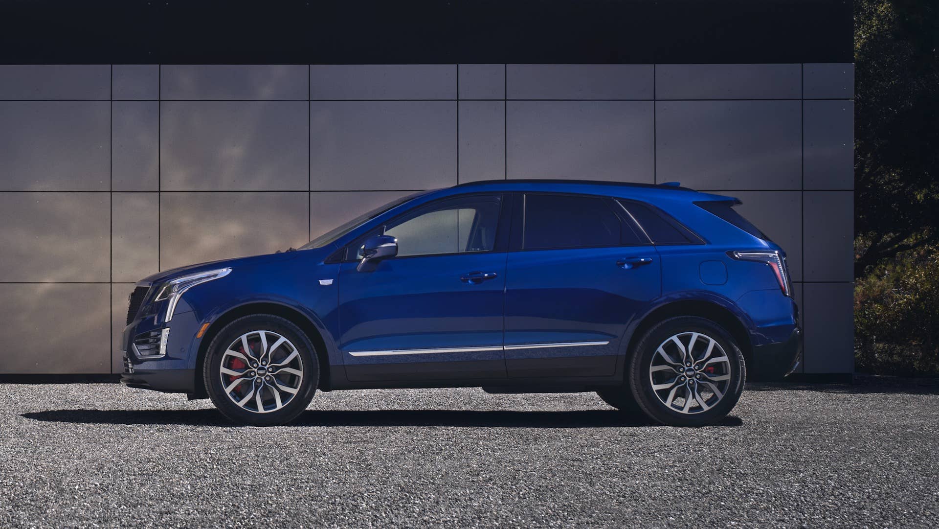Parked side view of the 2025 Cadillac XT5, shown in Opulent Blue Metallic, highlights its bold, modern look.