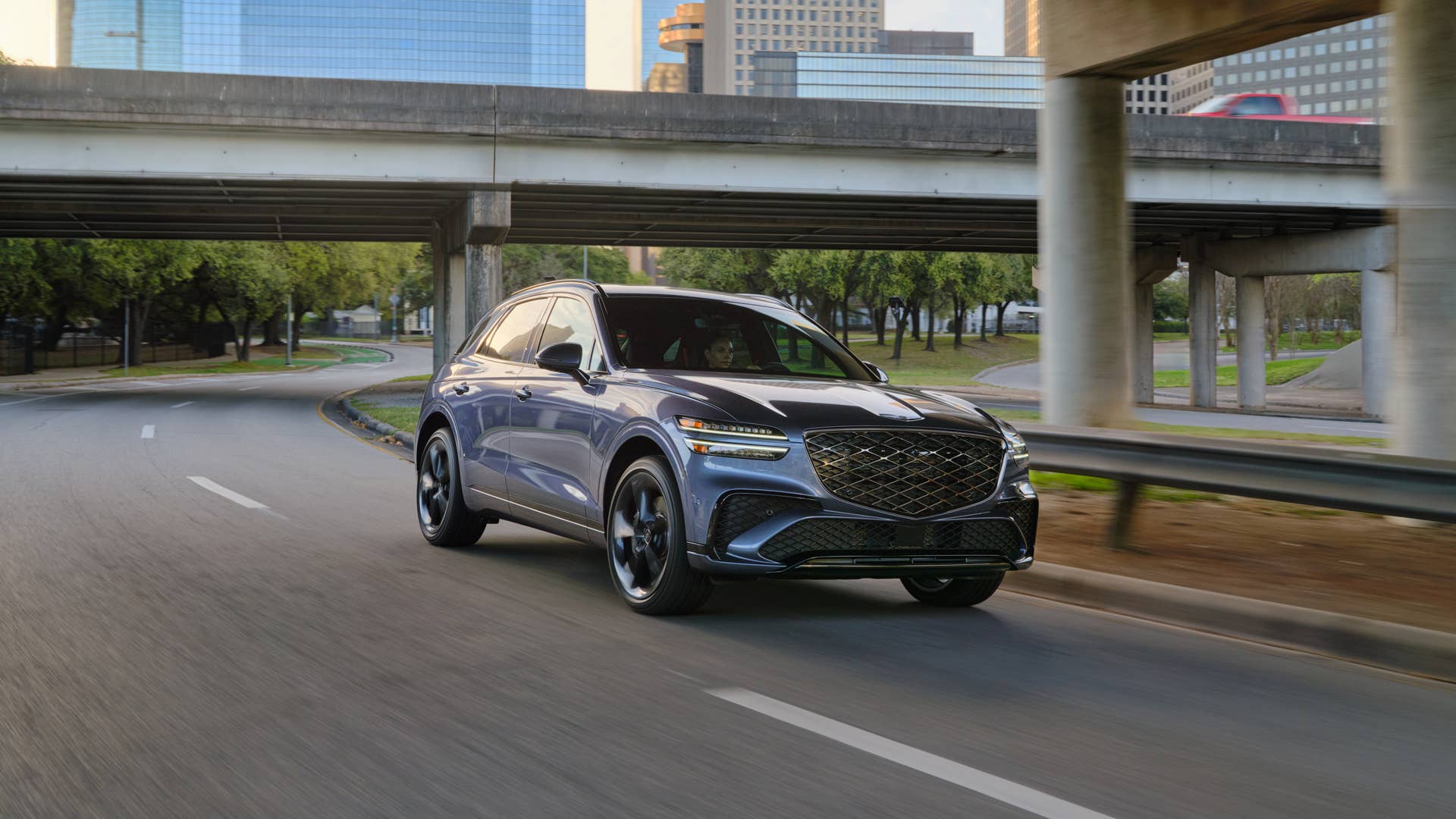 The front end of the 2026 Genesis GV70 3.5T Sport Prestige AWD driving under a bridge