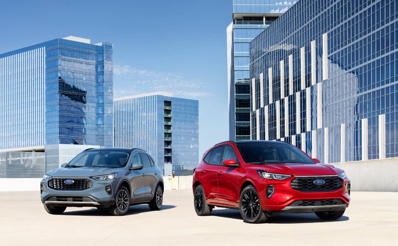 A blue Ford Escape plug-in-hybrid and a red Ford Escape ST Line Elite surrounded by glass fronted buildings