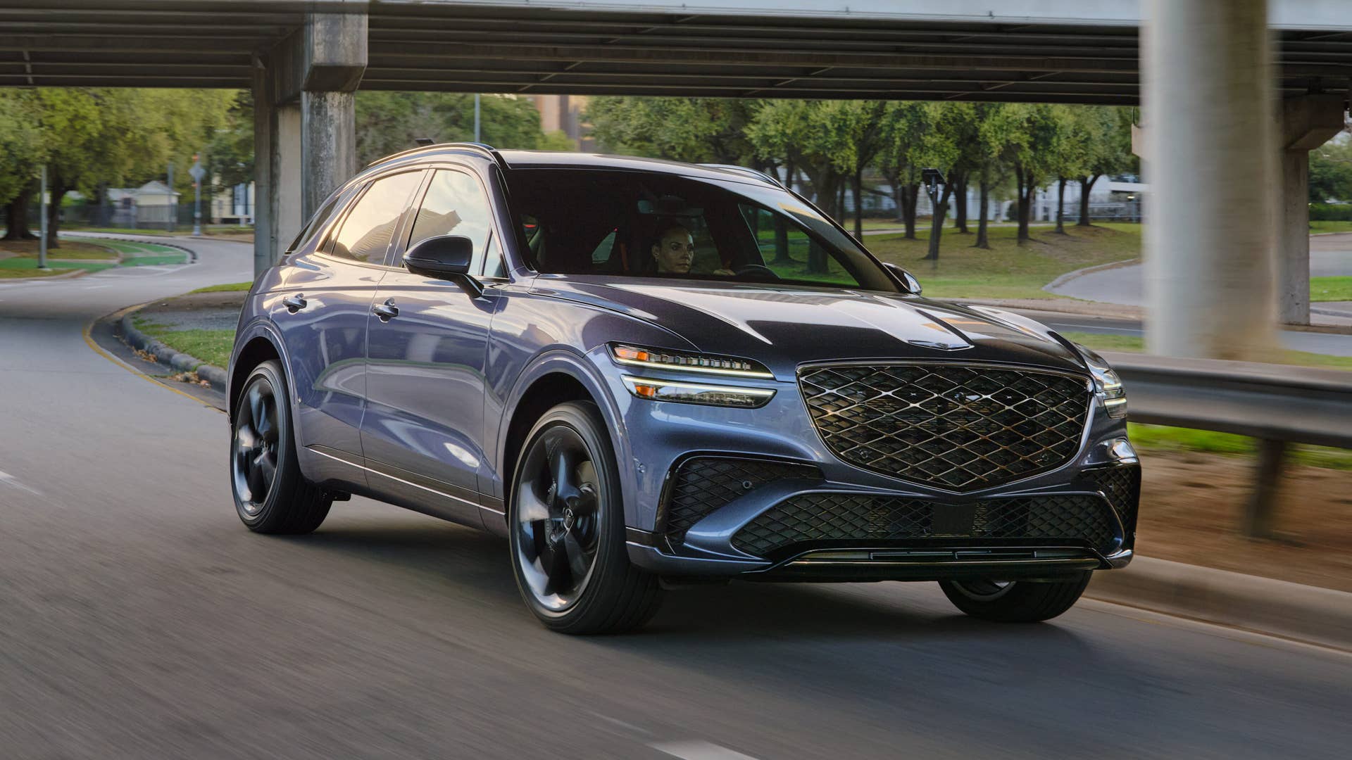The front end of the 2026 Genesis GV70 3.5T Sport Prestige AWD driving under a bridge