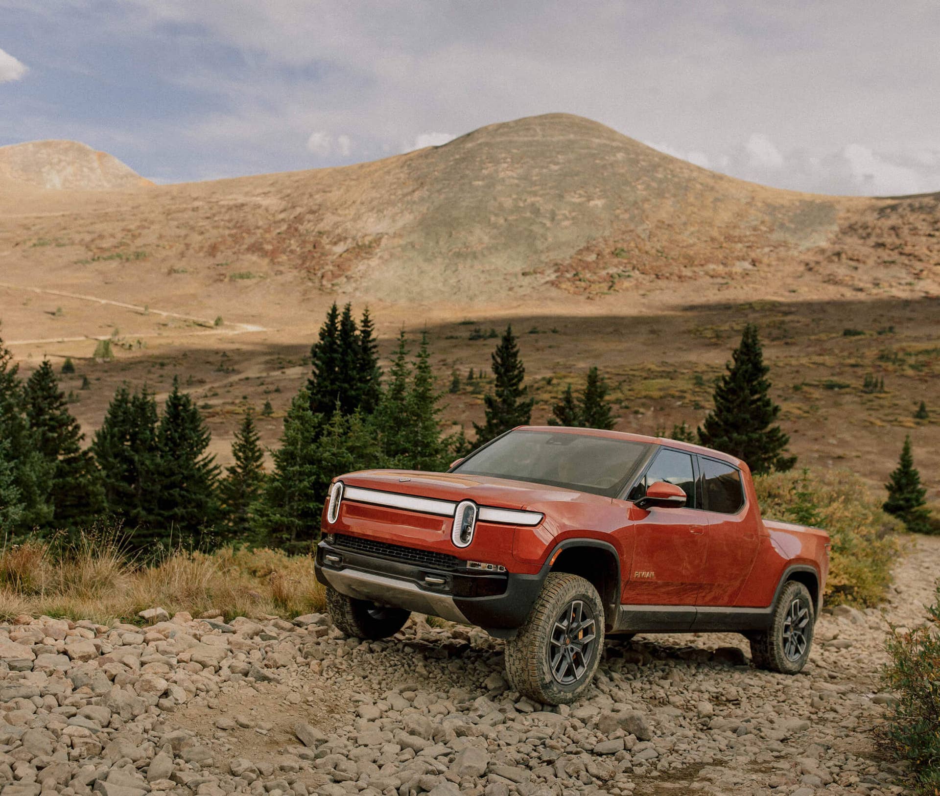 2026 Rivian R1T in Red Canyon front angled view off-road driving