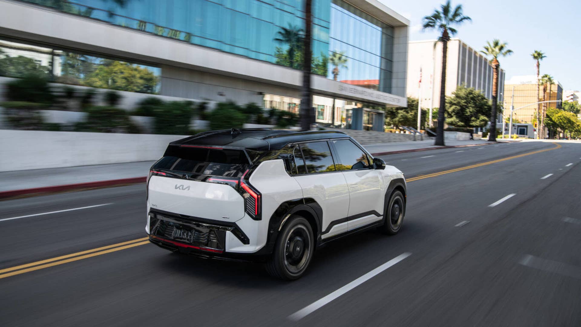 2027 Kia EV3 white rear angled view driving