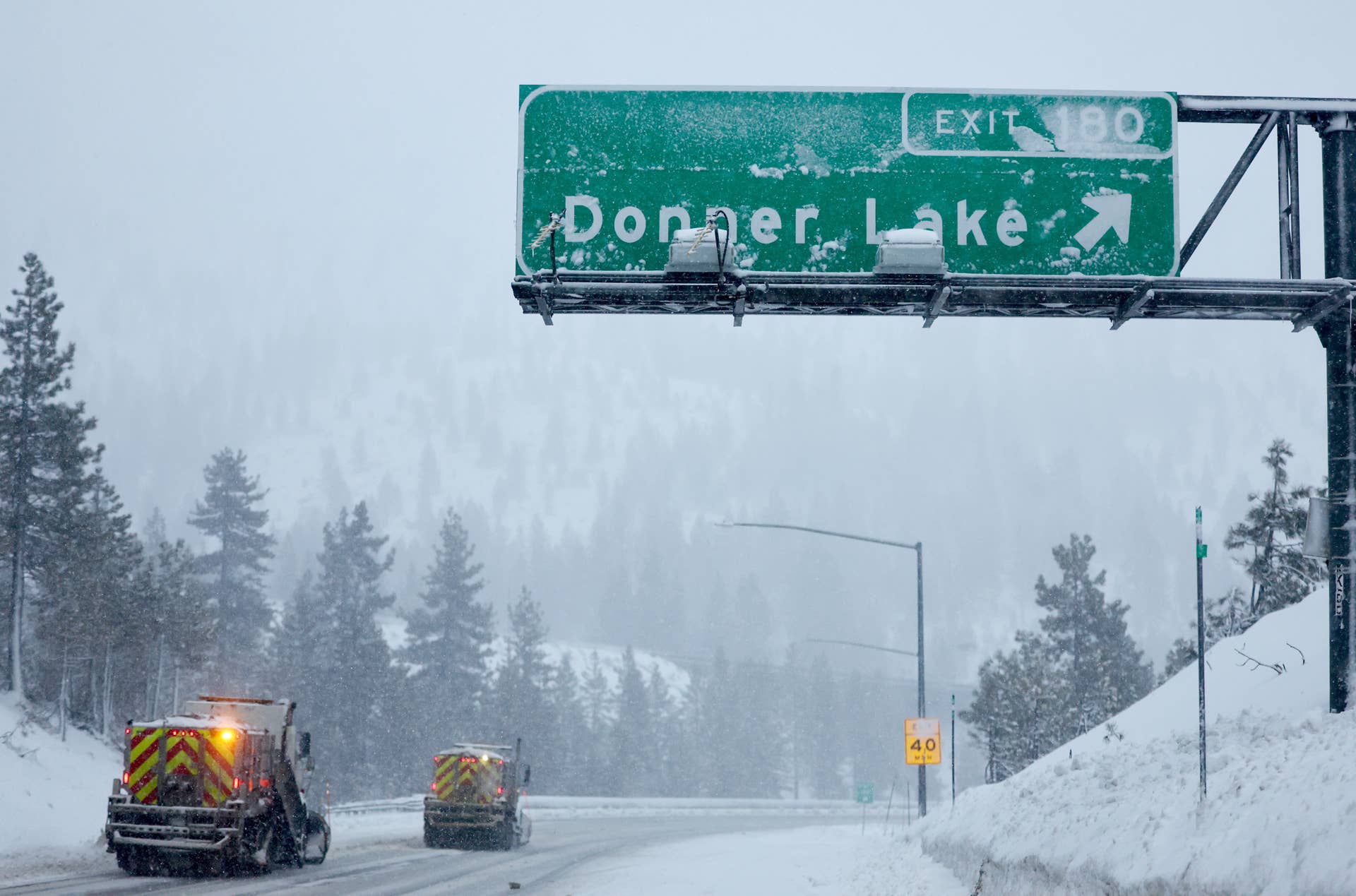 SODA SPRINGS, CALIFORNIA - FEBRUARY 29:  Snowplows operate beneath a sign for Donner Lake along Interstate 80 (I-80) in the Sierra Nevada mountains at the start of a powerful winter storm on February 29, 2024 near Soda Springs, California. Blizzard warnings have been issued with snowfall of up to 12 feet and wind gusts of up to 100 mph expected in some higher elevation locations during the multiple day storm. (Photo by Mario Tama/Getty Images)