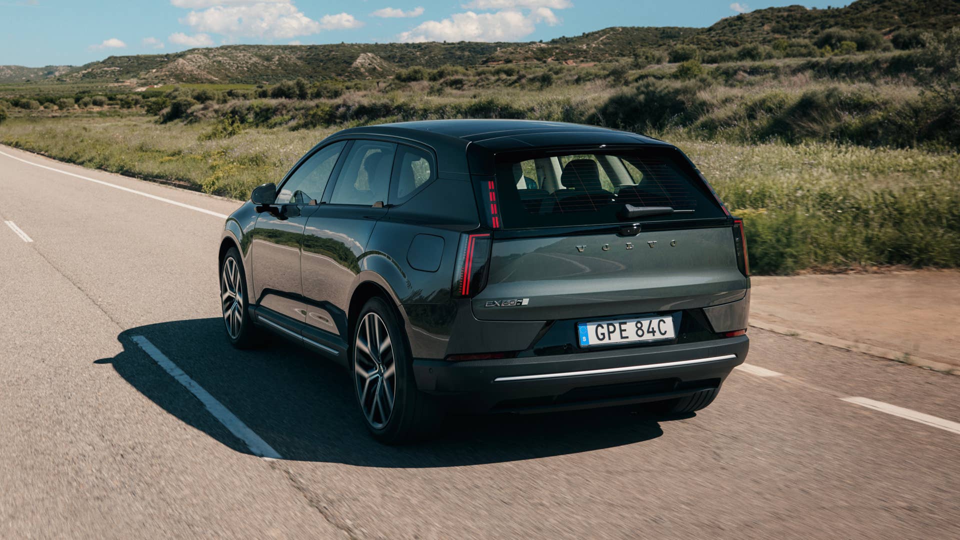 2027 Volvo EX60 green rear angled view driving