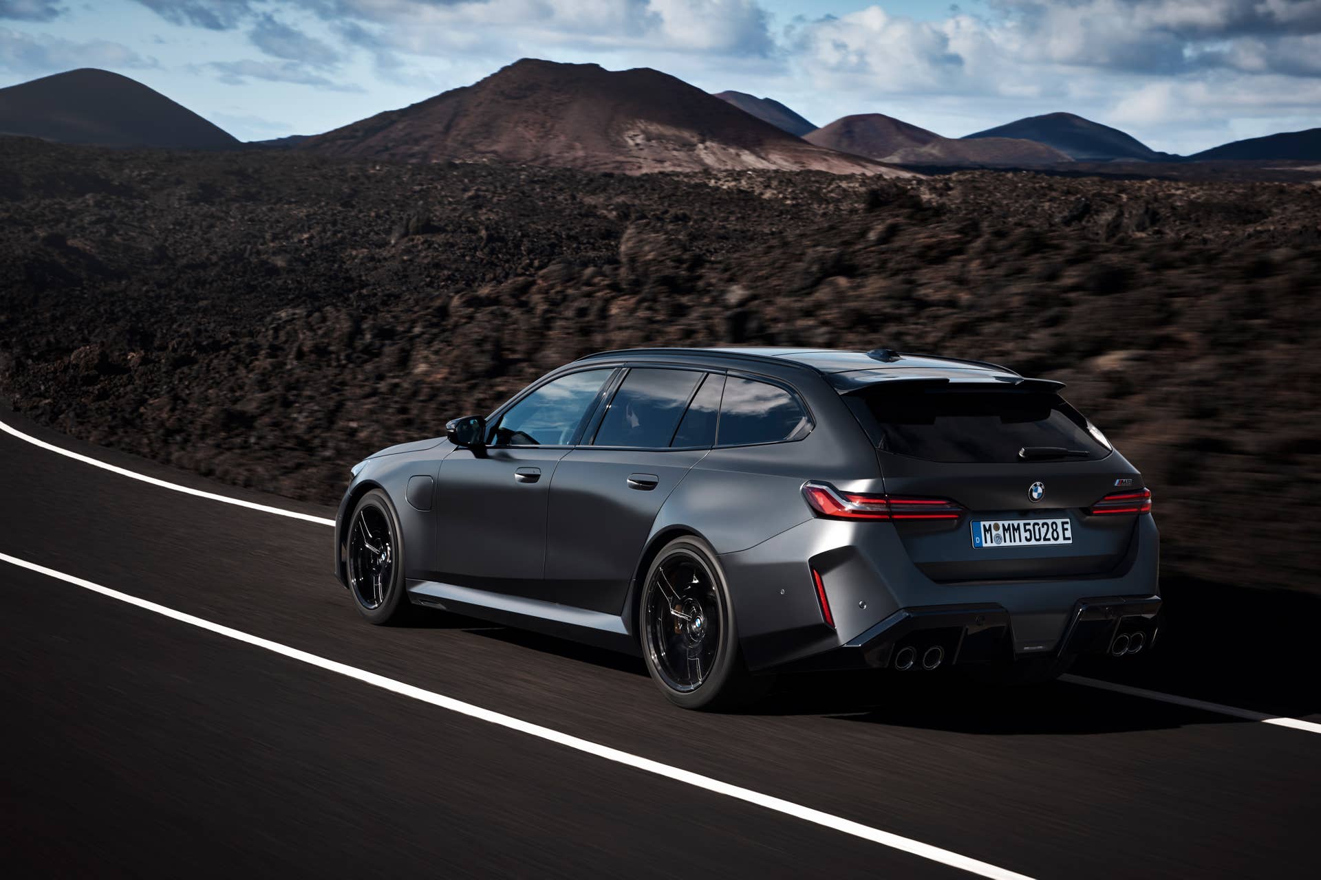 2026 BMW M5 Touring in BMW Individual Frozen Deep Grey rear angled view driving