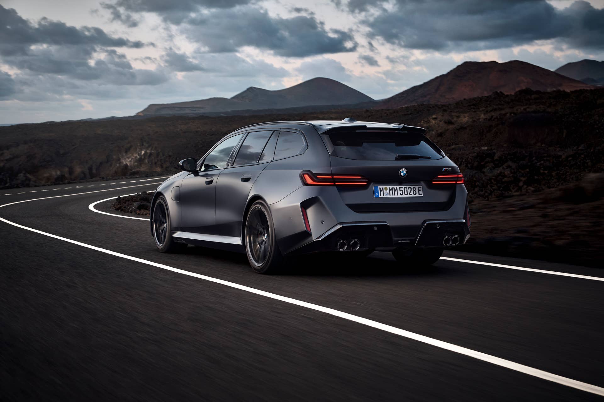 2026 BMW M5 Touring in BMW Individual Frozen Deep Grey rear angled view driving
