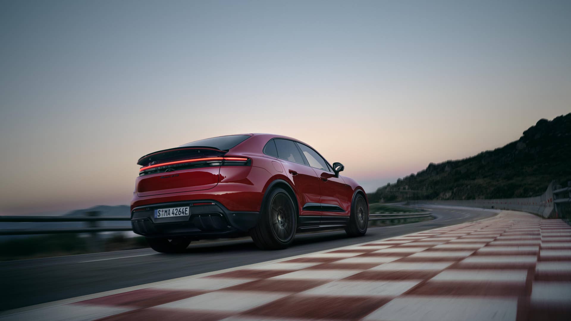 2026 Porsche Macan GTS in red rear angled view track driving