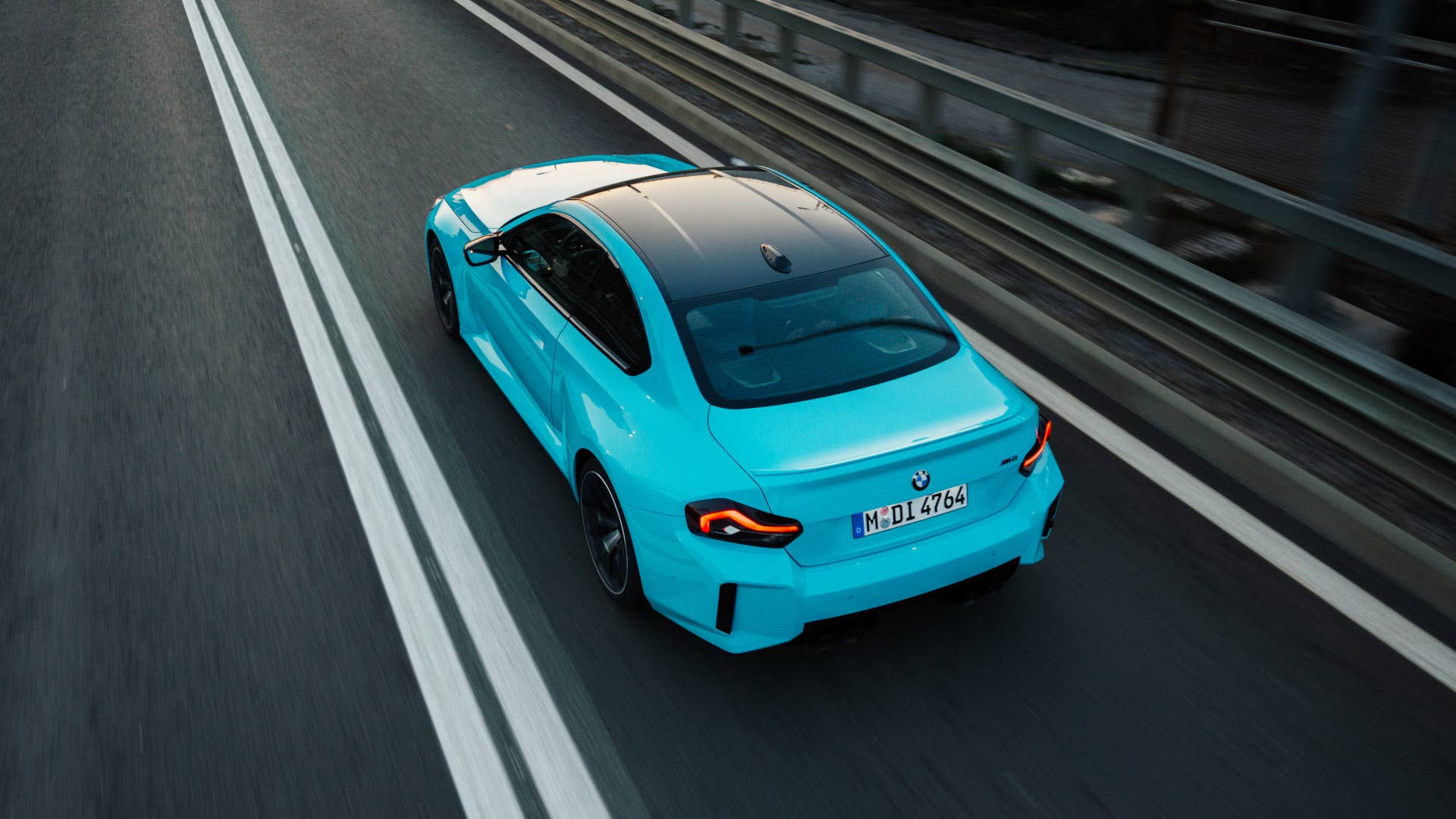 2027 BMW M2 xDrive in blue overhead rear angled view driving