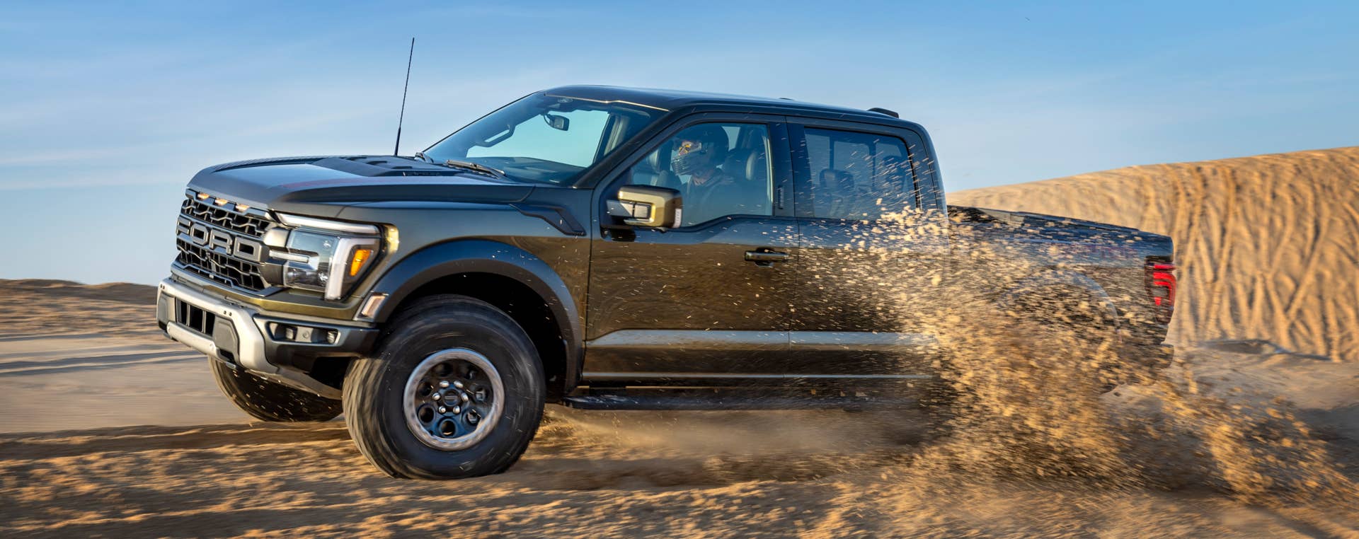 2025-2026 Ford F-150 Raptor in Agate Black side view sand driving
