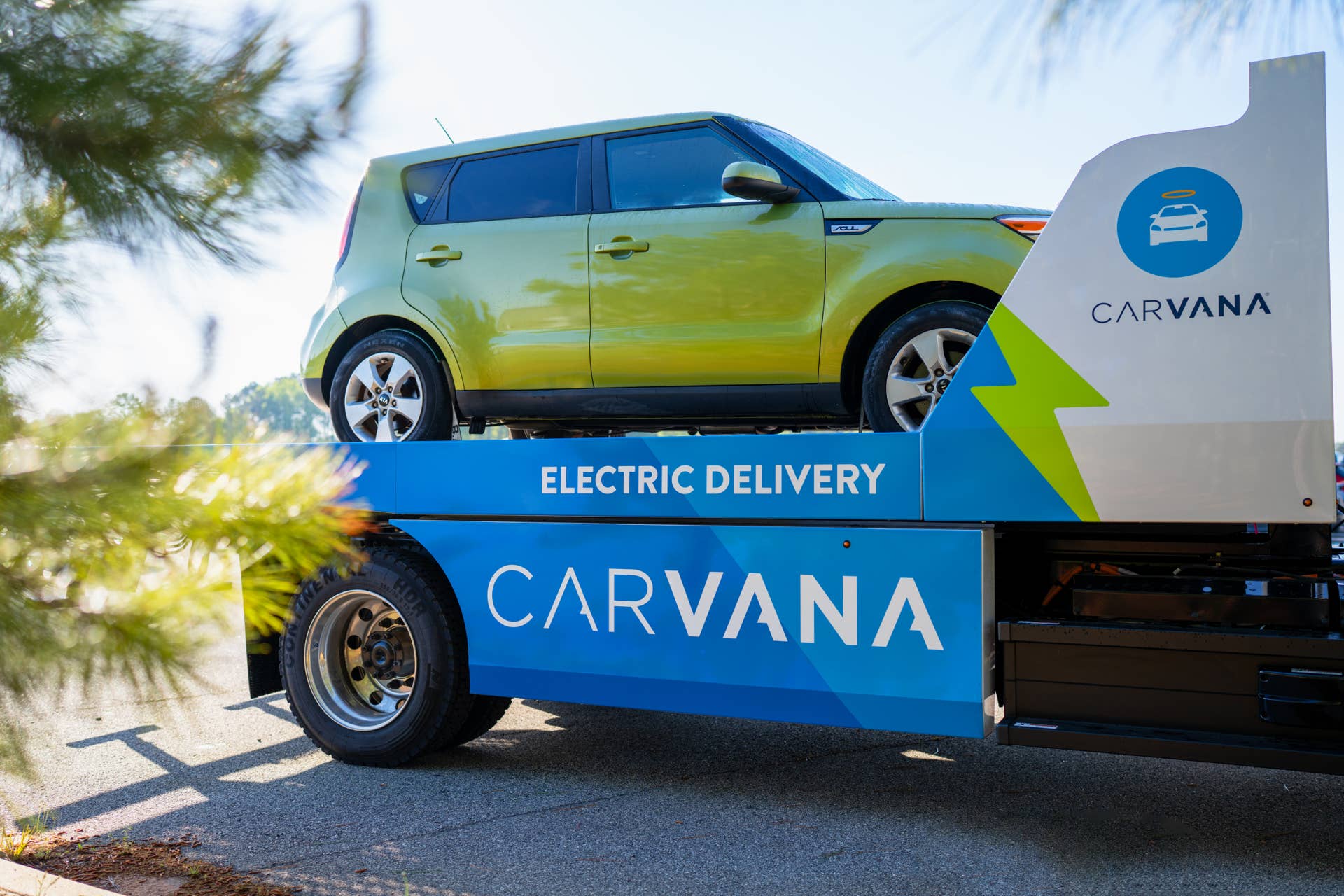 A Kia Soul EV being delivered by a Carvana truck