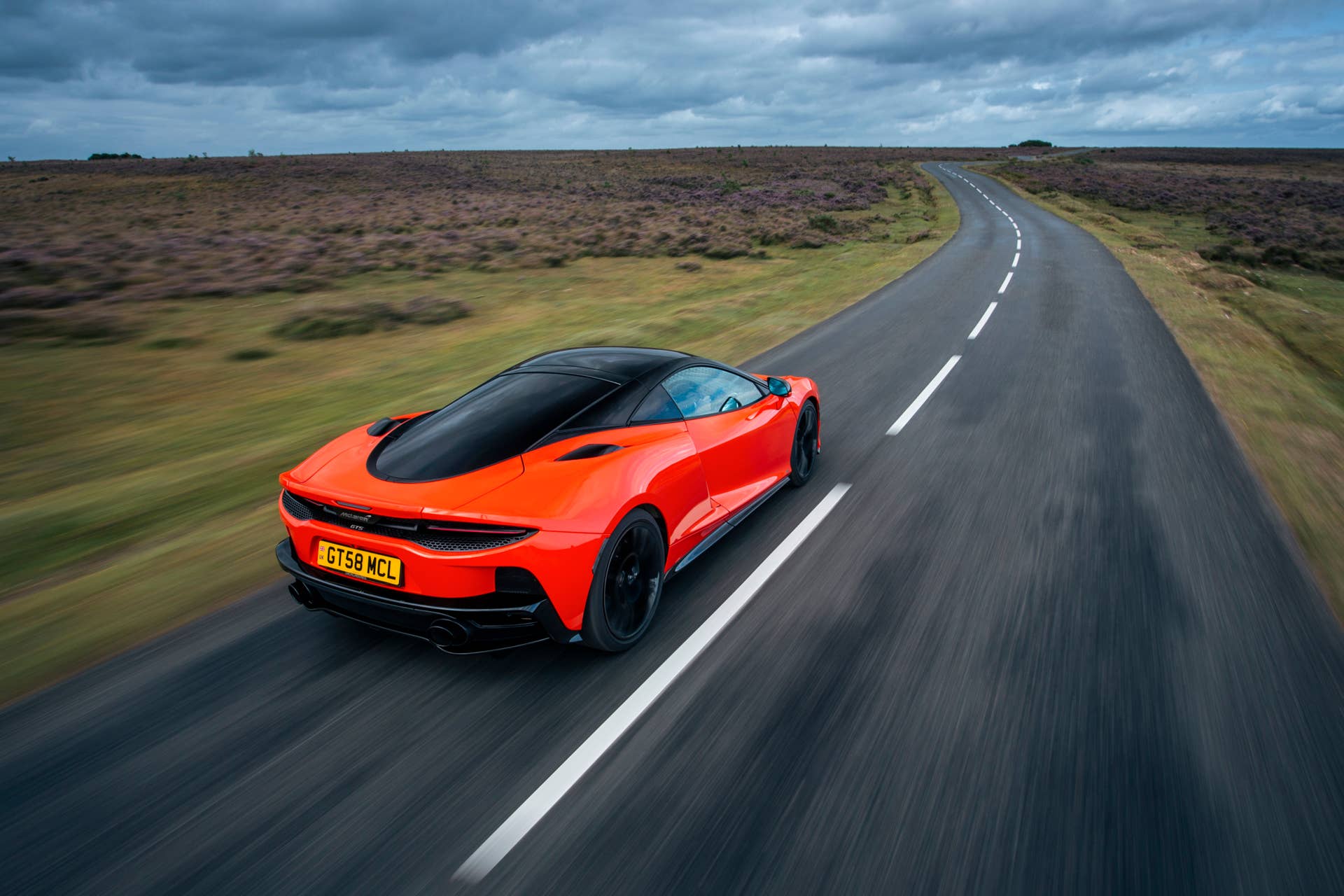 2025-2026 McLaren GTS in orange high rear angled view driving