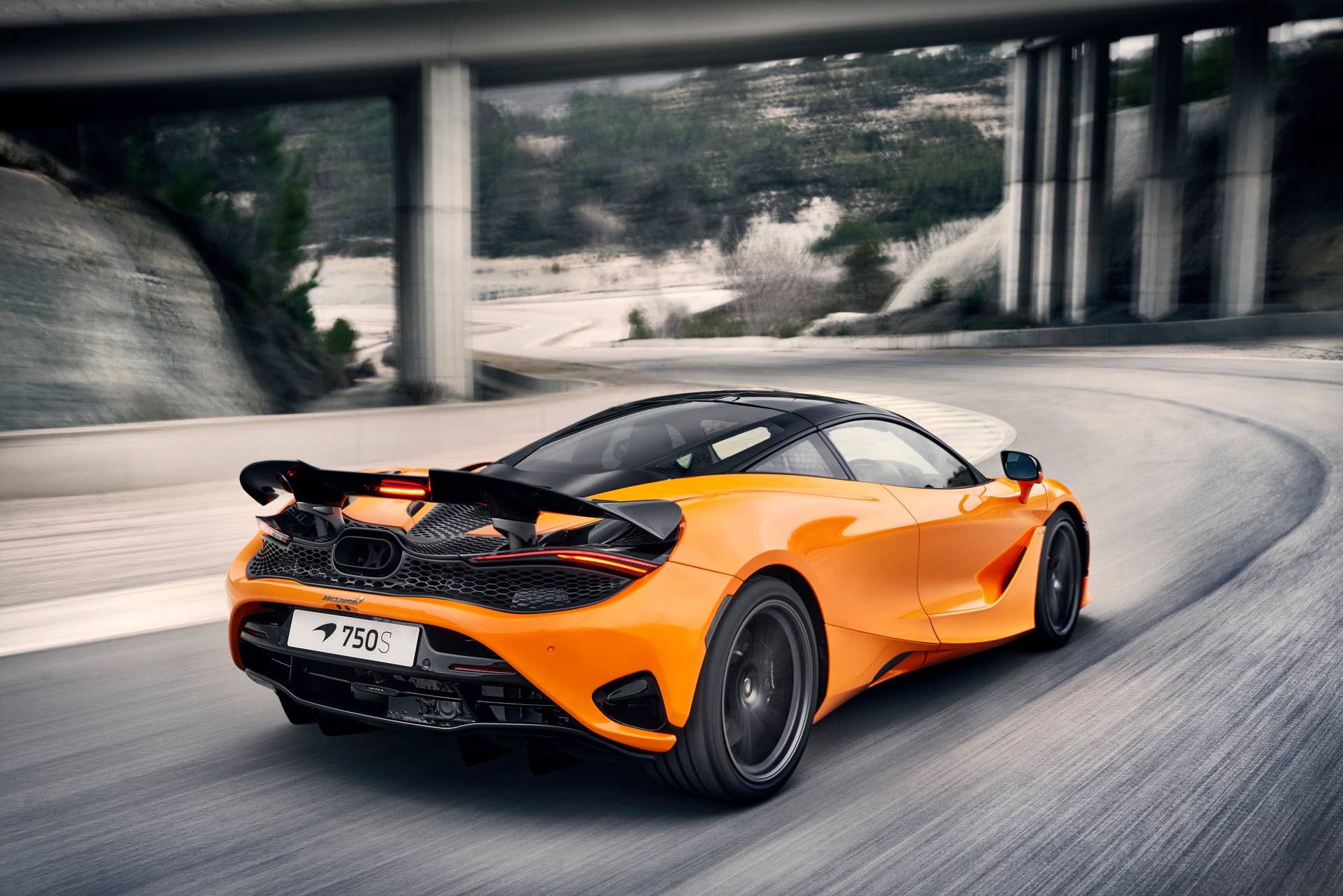 2025-2026 McLaren 750S in orange rear angled view driving