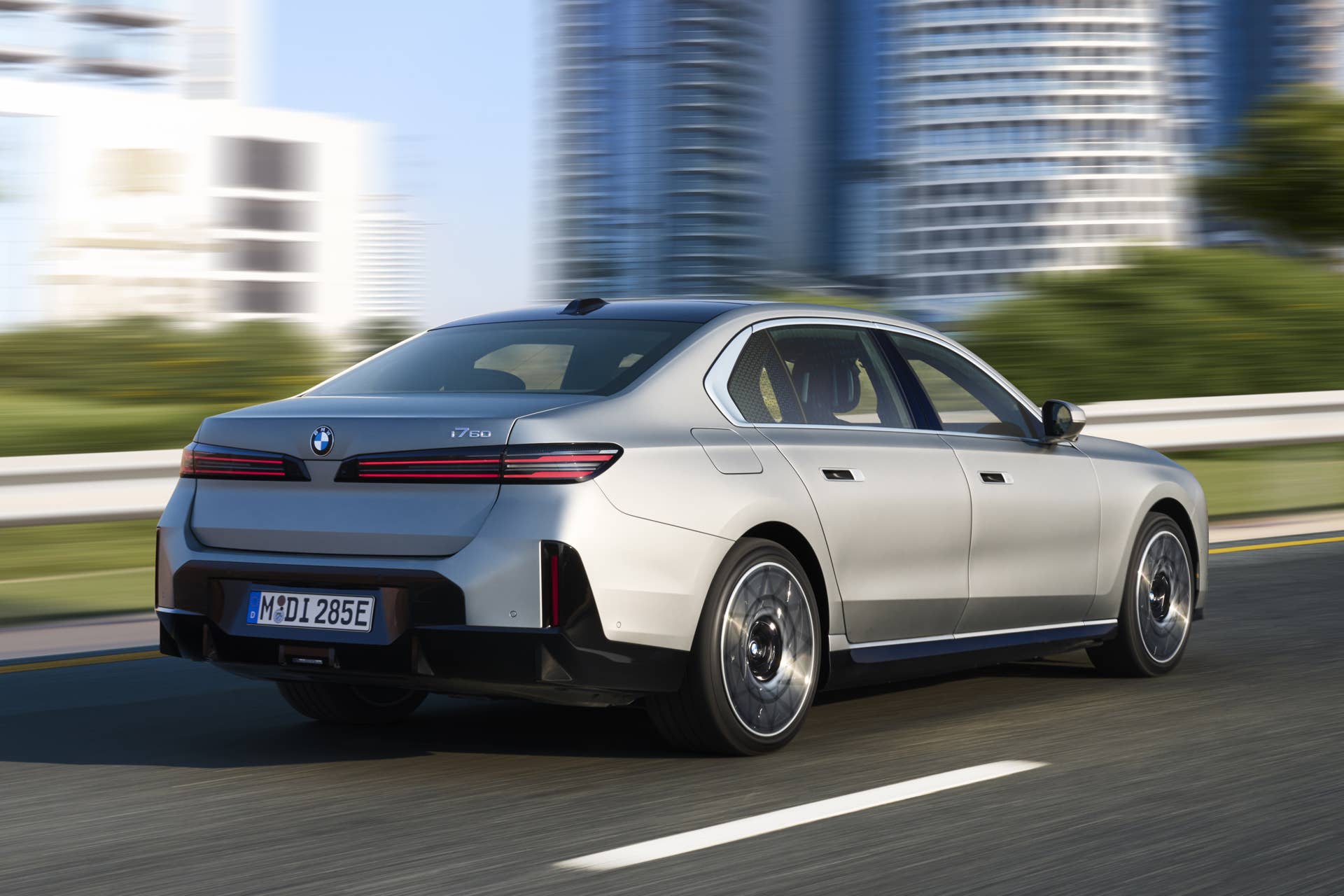 2027 BMW i7 60 xDrive in silver rear angled view driving